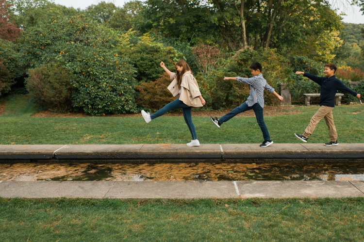 Esther and Thomas’ Fall family session at NJ Botanical Garden with three of their older children were so much to photograph since older kids tend to follow direction better. But I can not do cute little poses that I do with younger children. I thought to myself what would Wes Anderson do? Something more abstract and something fun. Bigger and older kids needed big actions and something not cheesy. Photographing older kids were bit challenging at first but I think we all had some fun and got some good photos for Esther and Thomas’ family. Esther and Thomas’ fall family session at NJ Botanical Garden photographed by Karis from Hey Karis. Photograph is like freezing time, motion in print, movie turned into a book.