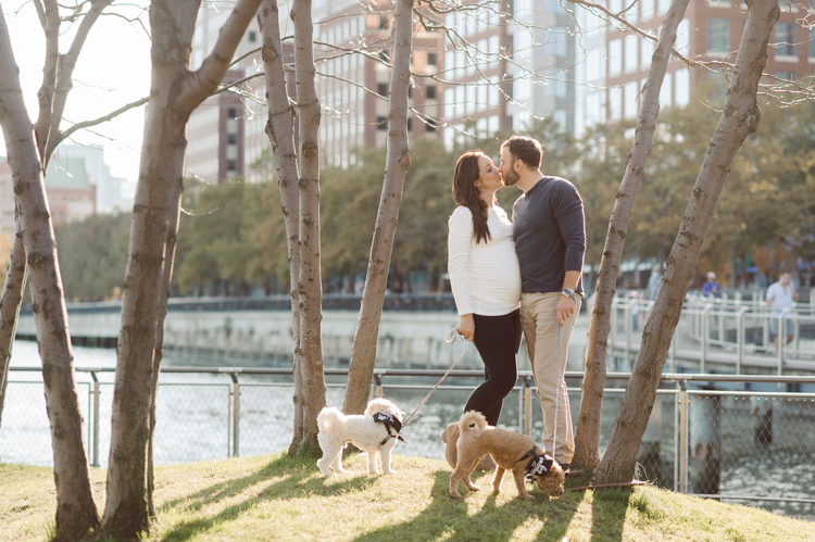 Very hot & sunny afternoon in November I met with Sam and Nick for the maternity session. This expecting parents brought their two fur babies out with them in the hopes of getting some photos of just four before the baby comes next months. Their puppies Cats and Cabo are shih-poos (shih Tzu and Toy Poodle mix) and are too adorable. With Case, Cabo walking along their parents sides we walked along the waterfront of Hoboken NJ. Sam was literally glowing like a porcelain doll and Nick looked so excited and a bit nervous for boy’s arrival. Sam and Nick’s maternity/family session in Hoboken NJ photographed by Karis from Hey Karis. Photograph is like freezing time, motion in print, movie turned into a book. Now booking 2021 and 2022 weddings.