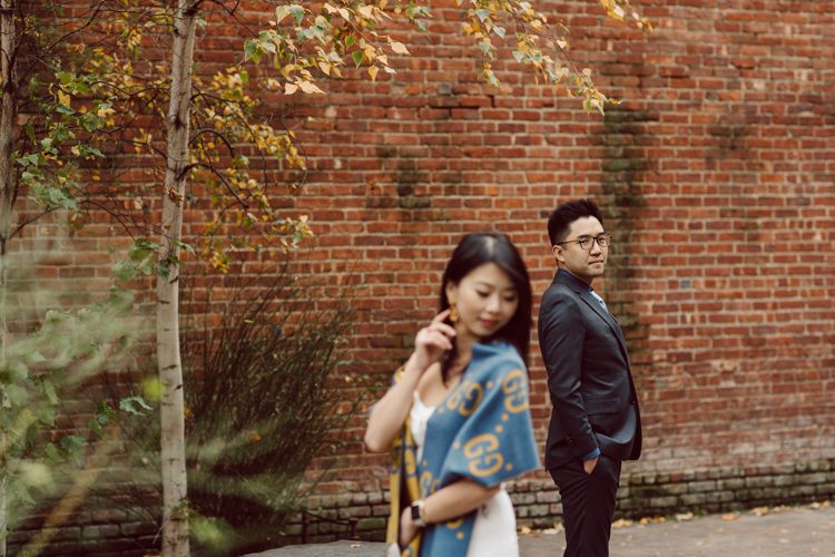 DUMBO Brooklyn NY photographing Stella and Peter's engagement. Temperature dropped dramatically, sky was covered in cloud and was windy but you can't possibly tell by Stella's chic outfit, white strap dress with white kitten heel mules and Peter in his suit and a Gucci tie. Per their outfits, my concept for Stella and Peter's engagement session geared to more editorial. As I shoot I tried to imagine a story in which I want to create and tell through my photos in every session. Stella and Peter's DUMBO Brooklyn Engagement Session captured by NY NJ Documentary Wedding Photographer Karis from Hey Karis, photographing your wedding moments cinematically.