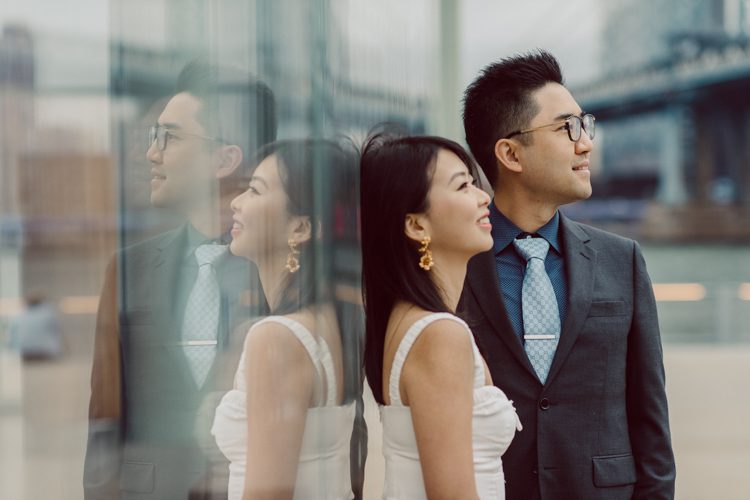 DUMBO Brooklyn NY photographing Stella and Peter's engagement. Temperature dropped dramatically, sky was covered in cloud and was windy but you can't possibly tell by Stella's chic outfit, white strap dress with white kitten heel mules and Peter in his suit and a Gucci tie. Per their outfits, my concept for Stella and Peter's engagement session geared to more editorial. As I shoot I tried to imagine a story in which I want to create and tell through my photos in every session. Stella and Peter's DUMBO Brooklyn Engagement Session captured by NY NJ Documentary Wedding Photographer Karis from Hey Karis, photographing your wedding moments cinematically.