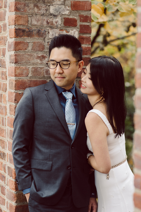 DUMBO Brooklyn NY photographing Stella and Peter's engagement. Temperature dropped dramatically, sky was covered in cloud and was windy but you can't possibly tell by Stella's chic outfit, white strap dress with white kitten heel mules and Peter in his suit and a Gucci tie. Per their outfits, my concept for Stella and Peter's engagement session geared to more editorial. As I shoot I tried to imagine a story in which I want to create and tell through my photos in every session. Stella and Peter's DUMBO Brooklyn Engagement Session captured by NY NJ Documentary Wedding Photographer Karis from Hey Karis, photographing your wedding moments cinematically.