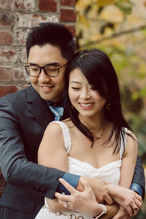DUMBO Brooklyn NY photographing Stella and Peter's engagement. Temperature dropped dramatically, sky was covered in cloud and was windy but you can't possibly tell by Stella's chic outfit, white strap dress with white kitten heel mules and Peter in his suit and a Gucci tie. Per their outfits, my concept for Stella and Peter's engagement session geared to more editorial. As I shoot I tried to imagine a story in which I want to create and tell through my photos in every session. Stella and Peter's DUMBO Brooklyn Engagement Session captured by NY NJ Documentary Wedding Photographer Karis from Hey Karis, photographing your wedding moments cinematically.