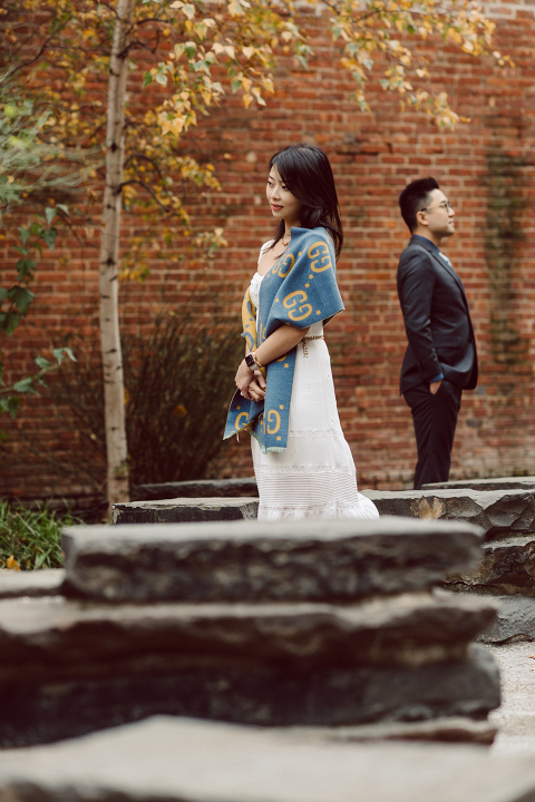DUMBO Brooklyn NY photographing Stella and Peter's engagement. Temperature dropped dramatically, sky was covered in cloud and was windy but you can't possibly tell by Stella's chic outfit, white strap dress with white kitten heel mules and Peter in his suit and a Gucci tie. Per their outfits, my concept for Stella and Peter's engagement session geared to more editorial. As I shoot I tried to imagine a story in which I want to create and tell through my photos in every session. Stella and Peter's DUMBO Brooklyn Engagement Session captured by NY NJ Documentary Wedding Photographer Karis from Hey Karis, photographing your wedding moments cinematically.