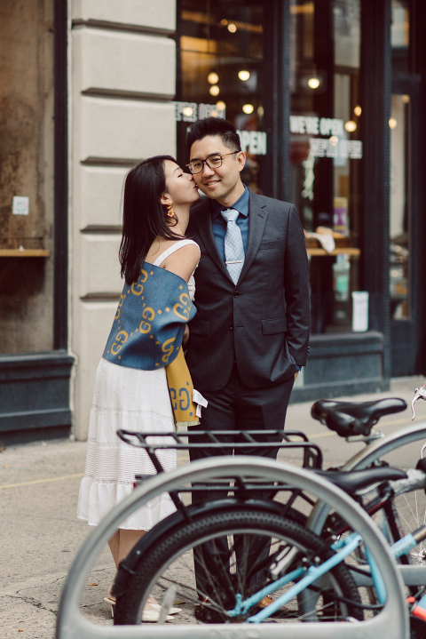 DUMBO Brooklyn NY photographing Stella and Peter's engagement. Temperature dropped dramatically, sky was covered in cloud and was windy but you can't possibly tell by Stella's chic outfit, white strap dress with white kitten heel mules and Peter in his suit and a Gucci tie. Per their outfits, my concept for Stella and Peter's engagement session geared to more editorial. As I shoot I tried to imagine a story in which I want to create and tell through my photos in every session. Stella and Peter's DUMBO Brooklyn Engagement Session captured by NY NJ Documentary Wedding Photographer Karis from Hey Karis, photographing your wedding moments cinematically.