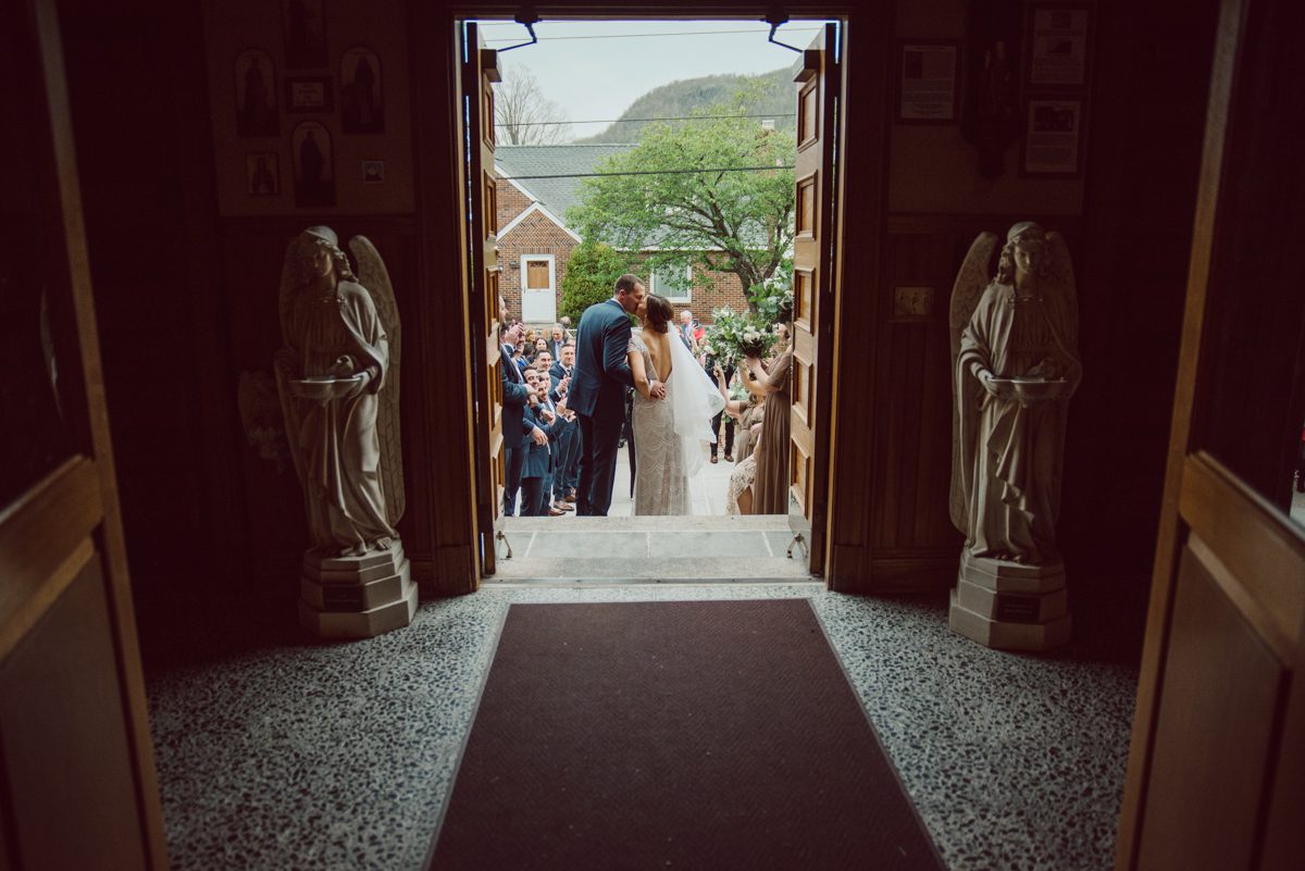 Pulled up to Michell's parents gorgeous mid-century home in Cold Spring, NY on Michelle and Robert's wedding day.  And Robert got ready at an airbnb nearby in Peekskill, NY. Even-though Michelle and Robert had some hiccup with their limo the whole village pulled together and transported Michell and Roberts along with their bridal party to the church Our Lady of Loretto Church to get Michelle and Robert married. Then everyone hoped onto everyone's cars to make their way to West Hills Country Club to party. Michelle and Robert weren't too into taking formal posed portraits but instead wanted to join their friends and guests to enjoy their wedding day, to party, to mingle, to drink and eat the food. Many candid moments were captured, and we wrapped the evening with the most stunning sunset across the field at West Hills Country Club. Michelle and Robert's West Hills Country Club Wedding captured by Hey Karis is NY, NJ, Brooklyn, Hudson Valley and Catskills Wedding and Elopement Photographer.