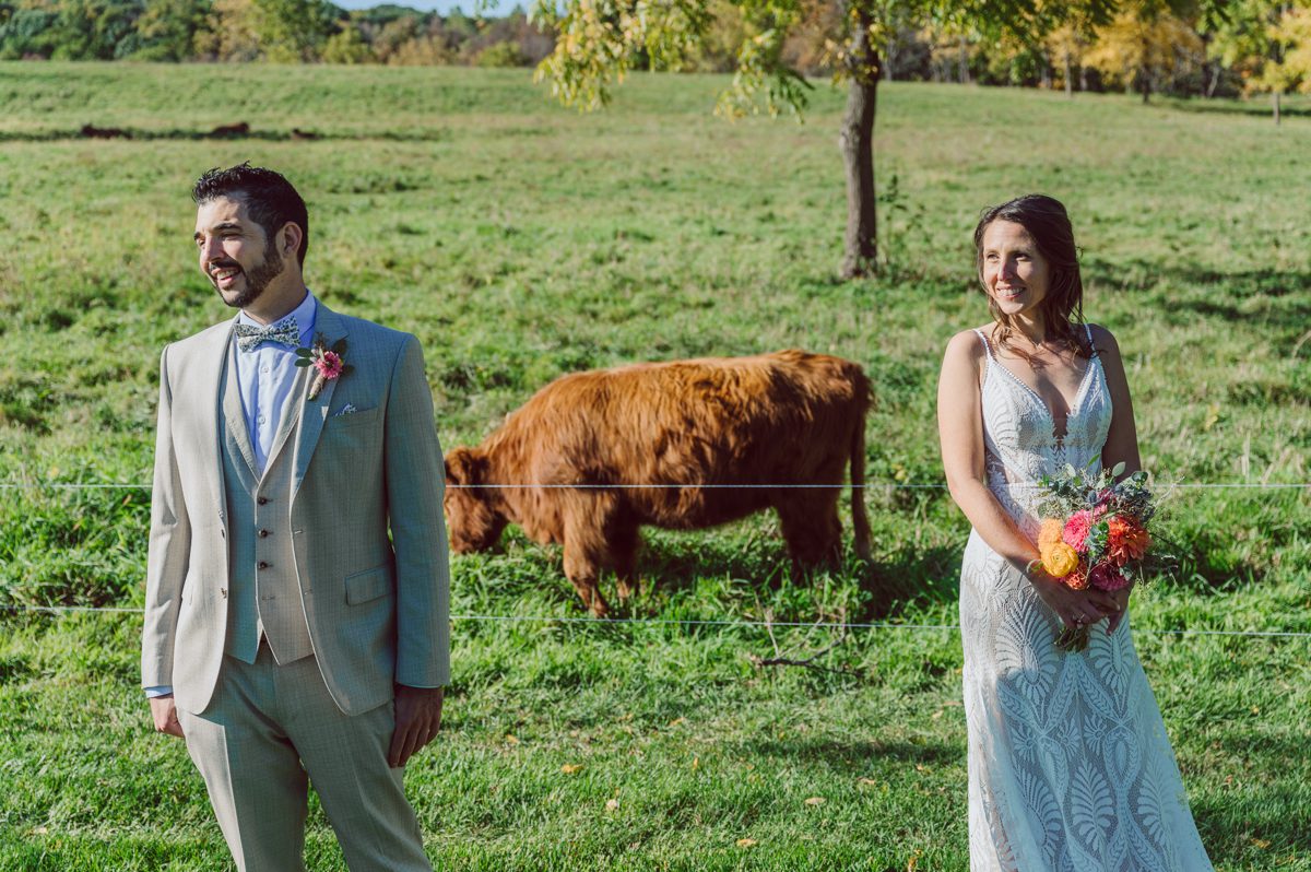Talking about climate change (global warming) we've been having weirdly warm almost hot Fall. So we were hoping so another warm day for Becca and Dan's wedding on October 8, 2022 but unfortunately non of us were that lucky and it was pretty chilly. Especially at The Farm at Glenwood Mountain NJ which is pretty Northern NJ it felt or was colder, windier and just chillier. Thankfully I brought the right jacket for the chilly wind on the top of Glenwood Mountain but OMG I felt so bad for my bride Becca only wearing her lace wedding dress standing outside on top of Glenwood Mountain during the wedding ceremony. But before I talk about the wedding ceremony let's start from Becca and Dan's wedding prep which took place onsite at The Farm at Glenwood Mountain in Sussex NJ. Becca got ready cozy in the bridal suit when Dan just got ready by the Barn at The Farm at Glenwood Mountain and we went straight into Becca and Dan's first look next to the Highland Cows! Cutest fluffy Highland Cows were all out by the field and chilled while we took some wedding portraits of Becca and Dan. One of the many reasons "I LOVE" this wedding venue "The Farm at Glenwood Mountain" is because of these adorable Fluffy Cows called Highland Cows! I can stare at the all day long and take photo of them all day long. After Becca and Dan's first look, wedding portraits and family photos were done I walked up to the hill to Becca and Dan's outdoor ceremony area on top of the hill at The Farm at Glenwood Mountain and along the way I saw more cute baby Highland Cows to photograph and stare and wave hello. Watched guests arrive in a Yellow School bus in any rustic Farm wedding style and was them walk up the hill. Following the path, the fence with The Barn at their backdrop. Sun was out, it was clear gorgeous day but bit chilly and definitely way windy on top of the hill. My groom Dan came up along with their dog Dash (Dasher), then finally Becca arrived with her parents along side her. Ceremony started quickly knowing that guests and bride probably are freezing, Wind kept moving the cloud in and out making me change my exposure non stop. Wind blew hard, moving Becca's hair all over the place. But non the less it was sincere and beautiful wedding ceremony surrounded by nature, trees and Highland Cows Becca and Dan said their wedding vows followed by I do's. Sealing the wedding ceremony with a kiss Becca and Dan walked down the aisle quickly as possible to bundle Becca in to something warm. Amazing food, spread and hors d'oeuvres were passed out and when the sun was setting everyone made their way in to the barn for warmth and to seated for Becca and Dan's wedding reception. Gorgeous structured barn at The Farm at Glenwood Mountain is definitely not your typical too rustic and broken down barn, the barn here is new, clean, architectural and gorgeous! The owner Chef Steve even makes everyone take off their shoes if we need to enter the barn before the reception. Just like that Becca and Dan danced and partied their way into the night and it was already time for their barn fire and s'mores time outside. Becca and Dan's The Farm at Glenwood Mountain Sussex NJ wedding captured by Karis from Hey Karis New York, Brooklyn, Hudson Valley and Catskills Wedding Photographer and NYC Elopement Photographer.
