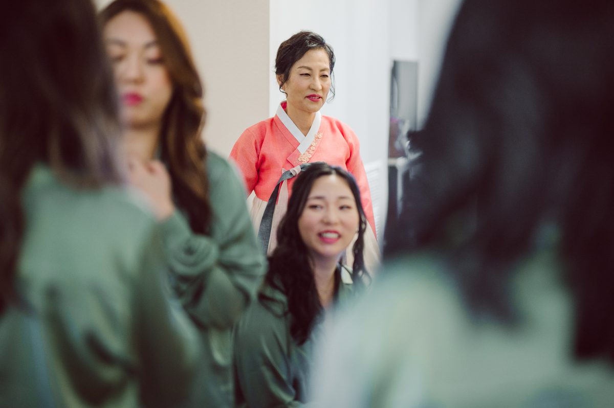 Duffield St, Brooklyn on November 19 even though it's Saturday morning it was still very busy. But luckily I found street parking right on Duffield St in front of Sheraton Downtown Brooklyn which was where I needed to be for Ariana and Jon's wedding prep. Vicky from VickyC5 hair/makeup team was there beautifying the ladies, I went straight to flat lays of Ariana's wedding details such as rings, jewelry and her wedding invitations. I use ribbons, extra loose flowers to make the flat lays more fine art looking. Once all the details are done, my full focus goes to the bride Ariana and her ladies. Ariana and Jon were planning to do a Chinese Door Game at the hotel room, so as soon as Ariana was ready in her Hanbok (Korean Traditional Wedding Outfit) Jon and his groomsmen arrived at the door. With Ariana's bridal suite crowded with too many people Ariana's bridesmaids started to give instructions to the games that Jon and his groomsmen need to play in order to get through the second door so that Jon can meet/see his bride Ariana. While the games are happening outside Ariana's door one of the bridesmaid has her phone on FaceTime so that Ariana can see how the men are doing during all the door games. I of course had my second shooter inside the room with Ariana to get her reactions which was hilarious. After the door games, we then moved to a conference room of at Sheraton Downtown Brooklyn for Ariana and Jon's Chinese Tea Pouring Ceremony (this is Jon's Chinese side's wedding tradition where you pour tea to all the elders in the family). Once all the Chines and Korean wedding traditions are over, we all rushed to Brooklyn Botanical Garden. Traffic from Sheraton Downtown Brooklyn to Brooklyn Botanical Garden was pretty bad, as usual. Once I arrived there of course was no street parking available near the entrance and parking lot for Brooklyn Botanical Garden was way too far for me to carry all the gears. After driving around I found one spot few blocks away from the Brooklyn Botanical Garden entrance. Brooklyn Botanical Garden was busy with Lightscape preparation and installation which we were not allowed to photograph so we were left with very little options for wedding portrait backdrop, plus it was COLD and we were looking light! These are important things to consider when you are planning for Winter wedding. I worked as quickly as possible with Ariana and Jon's first look and bridal party photos. Then we stayed inside for family photos since elders did not wanted to go outside which I totally don't blame. Then I quickly took Ariana and Jon outside for bit more couple's portraits then it was time for the wedding ceremony. Ariana and Jon's wedding ceremony held place at The Palm House at Brooklyn Botanical Garden, but because it was an winter wedding we've lost all the light and I had to use my video lights but over all the ceremony was beautiful and Oh Fleur NYC did absolutely an amazing job with ceremony decor (floral/candles). The Palm House was empty again, OhfleurNYC as well as Brooklyn Botanical Garden staff were busy turning the room. Oh Fleur NYC's Jessica's talent was amazing her usage of floral, choice of colors and mixing the floral with tall candles were magical. Turned The Palm House into a beautiful and romantic garden. Warmth of candles, peach and pinks of flowers all blended so well turning the Palm House at Brooklyn Botanical Garden in to fairytale floral ballroom. Ariana and Jon attended cocktail enjoying their time with friends and family before their wedding reception at The Palm House. Ariana and Jon's wedding at The Palm House at Brooklyn Botanical Garden documented by Karis from Hey Karis New York, Brooklyn, Hudson Valley and Catskills Wedding Photographer and NYC Elopement Photographer.