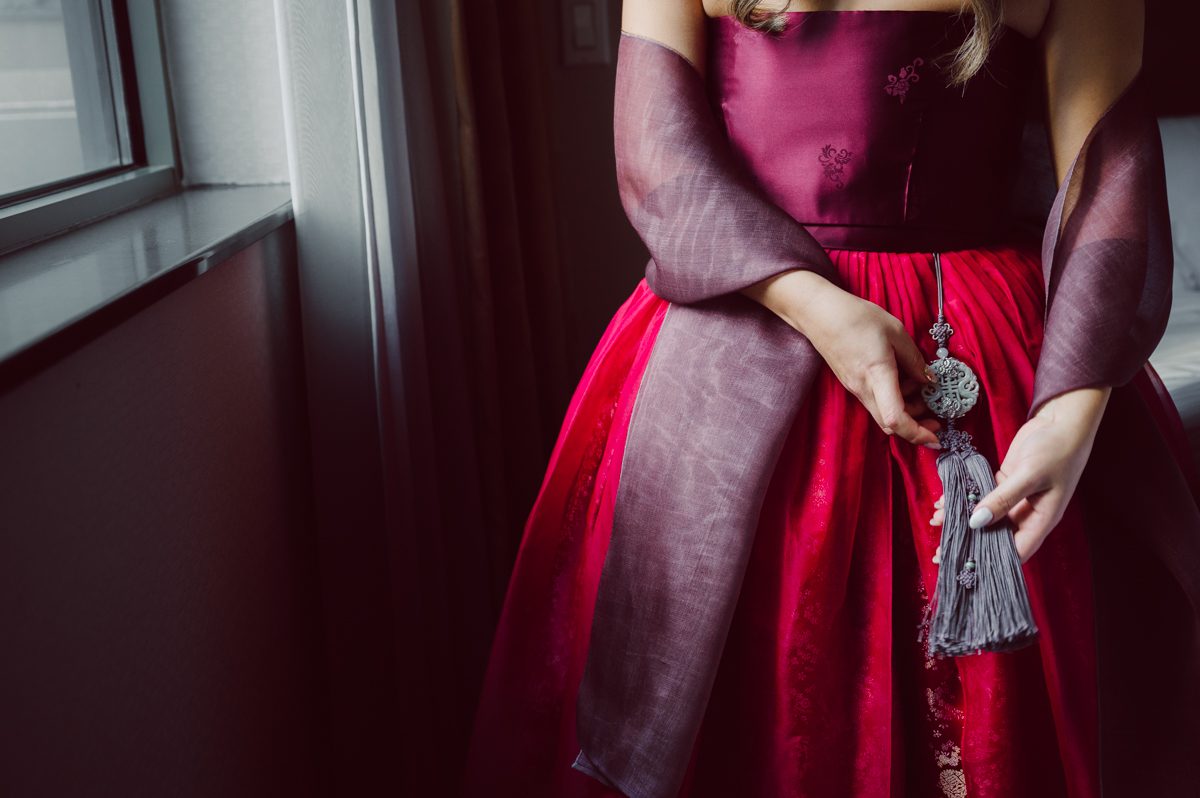 Duffield St, Brooklyn on November 19 even though it's Saturday morning it was still very busy. But luckily I found street parking right on Duffield St in front of Sheraton Downtown Brooklyn which was where I needed to be for Ariana and Jon's wedding prep. Vicky from VickyC5 hair/makeup team was there beautifying the ladies, I went straight to flat lays of Ariana's wedding details such as rings, jewelry and her wedding invitations. I use ribbons, extra loose flowers to make the flat lays more fine art looking. Once all the details are done, my full focus goes to the bride Ariana and her ladies. Ariana and Jon were planning to do a Chinese Door Game at the hotel room, so as soon as Ariana was ready in her Hanbok (Korean Traditional Wedding Outfit) Jon and his groomsmen arrived at the door. With Ariana's bridal suite crowded with too many people Ariana's bridesmaids started to give instructions to the games that Jon and his groomsmen need to play in order to get through the second door so that Jon can meet/see his bride Ariana. While the games are happening outside Ariana's door one of the bridesmaid has her phone on FaceTime so that Ariana can see how the men are doing during all the door games. I of course had my second shooter inside the room with Ariana to get her reactions which was hilarious. After the door games, we then moved to a conference room of at Sheraton Downtown Brooklyn for Ariana and Jon's Chinese Tea Pouring Ceremony (this is Jon's Chinese side's wedding tradition where you pour tea to all the elders in the family). Once all the Chines and Korean wedding traditions are over, we all rushed to Brooklyn Botanical Garden. Traffic from Sheraton Downtown Brooklyn to Brooklyn Botanical Garden was pretty bad, as usual. Once I arrived there of course was no street parking available near the entrance and parking lot for Brooklyn Botanical Garden was way too far for me to carry all the gears. After driving around I found one spot few blocks away from the Brooklyn Botanical Garden entrance. Brooklyn Botanical Garden was busy with Lightscape preparation and installation which we were not allowed to photograph so we were left with very little options for wedding portrait backdrop, plus it was COLD and we were looking light! These are important things to consider when you are planning for Winter wedding. I worked as quickly as possible with Ariana and Jon's first look and bridal party photos. Then we stayed inside for family photos since elders did not wanted to go outside which I totally don't blame. Then I quickly took Ariana and Jon outside for bit more couple's portraits then it was time for the wedding ceremony. Ariana and Jon's wedding ceremony held place at The Palm House at Brooklyn Botanical Garden, but because it was an winter wedding we've lost all the light and I had to use my video lights but over all the ceremony was beautiful and Oh Fleur NYC did absolutely an amazing job with ceremony decor (floral/candles). The Palm House was empty again, OhfleurNYC as well as Brooklyn Botanical Garden staff were busy turning the room. Oh Fleur NYC's Jessica's talent was amazing her usage of floral, choice of colors and mixing the floral with tall candles were magical. Turned The Palm House into a beautiful and romantic garden. Warmth of candles, peach and pinks of flowers all blended so well turning the Palm House at Brooklyn Botanical Garden in to fairytale floral ballroom. Ariana and Jon attended cocktail enjoying their time with friends and family before their wedding reception at The Palm House. Ariana and Jon's wedding at The Palm House at Brooklyn Botanical Garden documented by Karis from Hey Karis New York, Brooklyn, Hudson Valley and Catskills Wedding Photographer and NYC Elopement Photographer.