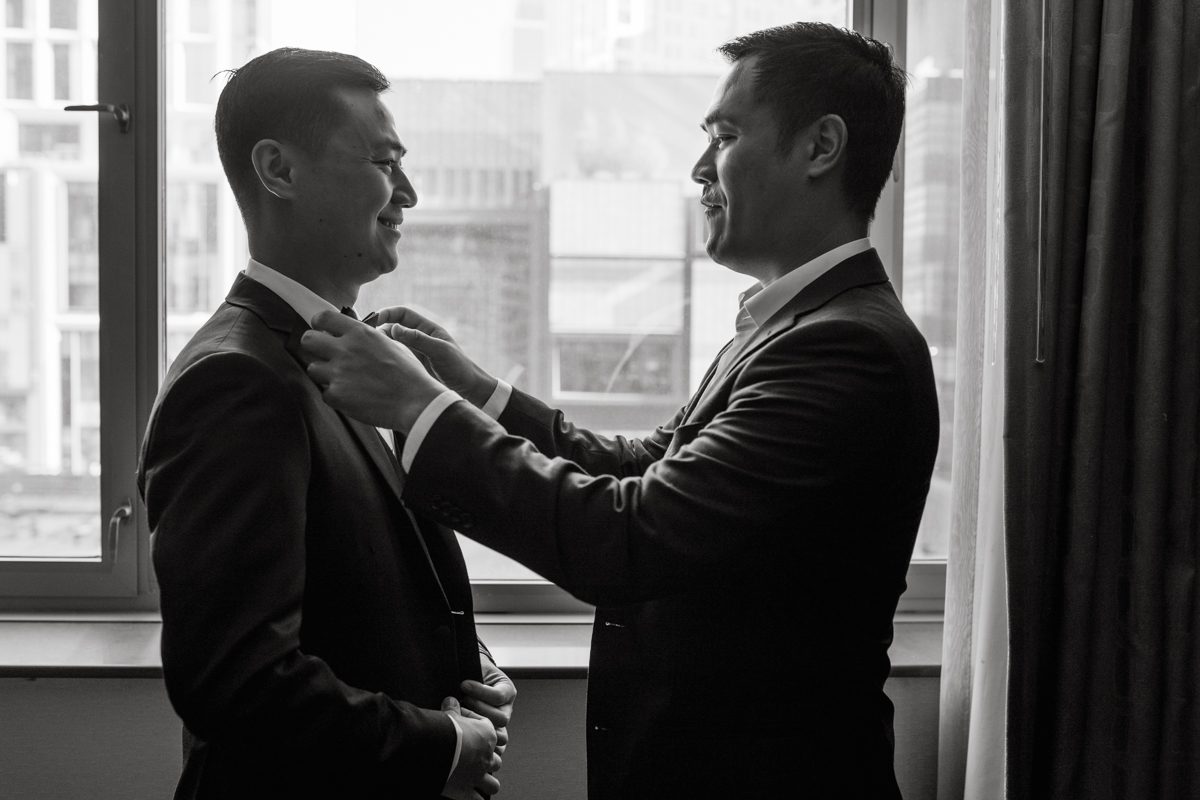 Duffield St, Brooklyn on November 19 even though it's Saturday morning it was still very busy. But luckily I found street parking right on Duffield St in front of Sheraton Downtown Brooklyn which was where I needed to be for Ariana and Jon's wedding prep. Vicky from VickyC5 hair/makeup team was there beautifying the ladies, I went straight to flat lays of Ariana's wedding details such as rings, jewelry and her wedding invitations. I use ribbons, extra loose flowers to make the flat lays more fine art looking. Once all the details are done, my full focus goes to the bride Ariana and her ladies. Ariana and Jon were planning to do a Chinese Door Game at the hotel room, so as soon as Ariana was ready in her Hanbok (Korean Traditional Wedding Outfit) Jon and his groomsmen arrived at the door. With Ariana's bridal suite crowded with too many people Ariana's bridesmaids started to give instructions to the games that Jon and his groomsmen need to play in order to get through the second door so that Jon can meet/see his bride Ariana. While the games are happening outside Ariana's door one of the bridesmaid has her phone on FaceTime so that Ariana can see how the men are doing during all the door games. I of course had my second shooter inside the room with Ariana to get her reactions which was hilarious. After the door games, we then moved to a conference room of at Sheraton Downtown Brooklyn for Ariana and Jon's Chinese Tea Pouring Ceremony (this is Jon's Chinese side's wedding tradition where you pour tea to all the elders in the family). Once all the Chines and Korean wedding traditions are over, we all rushed to Brooklyn Botanical Garden. Traffic from Sheraton Downtown Brooklyn to Brooklyn Botanical Garden was pretty bad, as usual. Once I arrived there of course was no street parking available near the entrance and parking lot for Brooklyn Botanical Garden was way too far for me to carry all the gears. After driving around I found one spot few blocks away from the Brooklyn Botanical Garden entrance. Brooklyn Botanical Garden was busy with Lightscape preparation and installation which we were not allowed to photograph so we were left with very little options for wedding portrait backdrop, plus it was COLD and we were looking light! These are important things to consider when you are planning for Winter wedding. I worked as quickly as possible with Ariana and Jon's first look and bridal party photos. Then we stayed inside for family photos since elders did not wanted to go outside which I totally don't blame. Then I quickly took Ariana and Jon outside for bit more couple's portraits then it was time for the wedding ceremony. Ariana and Jon's wedding ceremony held place at The Palm House at Brooklyn Botanical Garden, but because it was an winter wedding we've lost all the light and I had to use my video lights but over all the ceremony was beautiful and Oh Fleur NYC did absolutely an amazing job with ceremony decor (floral/candles). The Palm House was empty again, OhfleurNYC as well as Brooklyn Botanical Garden staff were busy turning the room. Oh Fleur NYC's Jessica's talent was amazing her usage of floral, choice of colors and mixing the floral with tall candles were magical. Turned The Palm House into a beautiful and romantic garden. Warmth of candles, peach and pinks of flowers all blended so well turning the Palm House at Brooklyn Botanical Garden in to fairytale floral ballroom. Ariana and Jon attended cocktail enjoying their time with friends and family before their wedding reception at The Palm House. Ariana and Jon's wedding at The Palm House at Brooklyn Botanical Garden documented by Karis from Hey Karis New York, Brooklyn, Hudson Valley and Catskills Wedding Photographer and NYC Elopement Photographer.