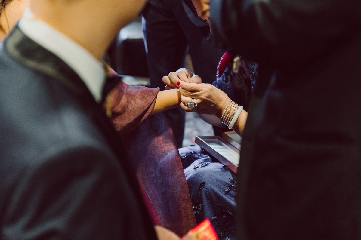 Duffield St, Brooklyn on November 19 even though it's Saturday morning it was still very busy. But luckily I found street parking right on Duffield St in front of Sheraton Downtown Brooklyn which was where I needed to be for Ariana and Jon's wedding prep. Vicky from VickyC5 hair/makeup team was there beautifying the ladies, I went straight to flat lays of Ariana's wedding details such as rings, jewelry and her wedding invitations. I use ribbons, extra loose flowers to make the flat lays more fine art looking. Once all the details are done, my full focus goes to the bride Ariana and her ladies. Ariana and Jon were planning to do a Chinese Door Game at the hotel room, so as soon as Ariana was ready in her Hanbok (Korean Traditional Wedding Outfit) Jon and his groomsmen arrived at the door. With Ariana's bridal suite crowded with too many people Ariana's bridesmaids started to give instructions to the games that Jon and his groomsmen need to play in order to get through the second door so that Jon can meet/see his bride Ariana. While the games are happening outside Ariana's door one of the bridesmaid has her phone on FaceTime so that Ariana can see how the men are doing during all the door games. I of course had my second shooter inside the room with Ariana to get her reactions which was hilarious. After the door games, we then moved to a conference room of at Sheraton Downtown Brooklyn for Ariana and Jon's Chinese Tea Pouring Ceremony (this is Jon's Chinese side's wedding tradition where you pour tea to all the elders in the family). Once all the Chines and Korean wedding traditions are over, we all rushed to Brooklyn Botanical Garden. Traffic from Sheraton Downtown Brooklyn to Brooklyn Botanical Garden was pretty bad, as usual. Once I arrived there of course was no street parking available near the entrance and parking lot for Brooklyn Botanical Garden was way too far for me to carry all the gears. After driving around I found one spot few blocks away from the Brooklyn Botanical Garden entrance. Brooklyn Botanical Garden was busy with Lightscape preparation and installation which we were not allowed to photograph so we were left with very little options for wedding portrait backdrop, plus it was COLD and we were looking light! These are important things to consider when you are planning for Winter wedding. I worked as quickly as possible with Ariana and Jon's first look and bridal party photos. Then we stayed inside for family photos since elders did not wanted to go outside which I totally don't blame. Then I quickly took Ariana and Jon outside for bit more couple's portraits then it was time for the wedding ceremony. Ariana and Jon's wedding ceremony held place at The Palm House at Brooklyn Botanical Garden, but because it was an winter wedding we've lost all the light and I had to use my video lights but over all the ceremony was beautiful and Oh Fleur NYC did absolutely an amazing job with ceremony decor (floral/candles). The Palm House was empty again, OhfleurNYC as well as Brooklyn Botanical Garden staff were busy turning the room. Oh Fleur NYC's Jessica's talent was amazing her usage of floral, choice of colors and mixing the floral with tall candles were magical. Turned The Palm House into a beautiful and romantic garden. Warmth of candles, peach and pinks of flowers all blended so well turning the Palm House at Brooklyn Botanical Garden in to fairytale floral ballroom. Ariana and Jon attended cocktail enjoying their time with friends and family before their wedding reception at The Palm House. Ariana and Jon's wedding at The Palm House at Brooklyn Botanical Garden documented by Karis from Hey Karis New York, Brooklyn, Hudson Valley and Catskills Wedding Photographer and NYC Elopement Photographer.