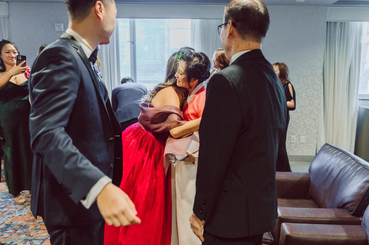 Duffield St, Brooklyn on November 19 even though it's Saturday morning it was still very busy. But luckily I found street parking right on Duffield St in front of Sheraton Downtown Brooklyn which was where I needed to be for Ariana and Jon's wedding prep. Vicky from VickyC5 hair/makeup team was there beautifying the ladies, I went straight to flat lays of Ariana's wedding details such as rings, jewelry and her wedding invitations. I use ribbons, extra loose flowers to make the flat lays more fine art looking. Once all the details are done, my full focus goes to the bride Ariana and her ladies. Ariana and Jon were planning to do a Chinese Door Game at the hotel room, so as soon as Ariana was ready in her Hanbok (Korean Traditional Wedding Outfit) Jon and his groomsmen arrived at the door. With Ariana's bridal suite crowded with too many people Ariana's bridesmaids started to give instructions to the games that Jon and his groomsmen need to play in order to get through the second door so that Jon can meet/see his bride Ariana. While the games are happening outside Ariana's door one of the bridesmaid has her phone on FaceTime so that Ariana can see how the men are doing during all the door games. I of course had my second shooter inside the room with Ariana to get her reactions which was hilarious. After the door games, we then moved to a conference room of at Sheraton Downtown Brooklyn for Ariana and Jon's Chinese Tea Pouring Ceremony (this is Jon's Chinese side's wedding tradition where you pour tea to all the elders in the family). Once all the Chines and Korean wedding traditions are over, we all rushed to Brooklyn Botanical Garden. Traffic from Sheraton Downtown Brooklyn to Brooklyn Botanical Garden was pretty bad, as usual. Once I arrived there of course was no street parking available near the entrance and parking lot for Brooklyn Botanical Garden was way too far for me to carry all the gears. After driving around I found one spot few blocks away from the Brooklyn Botanical Garden entrance. Brooklyn Botanical Garden was busy with Lightscape preparation and installation which we were not allowed to photograph so we were left with very little options for wedding portrait backdrop, plus it was COLD and we were looking light! These are important things to consider when you are planning for Winter wedding. I worked as quickly as possible with Ariana and Jon's first look and bridal party photos. Then we stayed inside for family photos since elders did not wanted to go outside which I totally don't blame. Then I quickly took Ariana and Jon outside for bit more couple's portraits then it was time for the wedding ceremony. Ariana and Jon's wedding ceremony held place at The Palm House at Brooklyn Botanical Garden, but because it was an winter wedding we've lost all the light and I had to use my video lights but over all the ceremony was beautiful and Oh Fleur NYC did absolutely an amazing job with ceremony decor (floral/candles). The Palm House was empty again, OhfleurNYC as well as Brooklyn Botanical Garden staff were busy turning the room. Oh Fleur NYC's Jessica's talent was amazing her usage of floral, choice of colors and mixing the floral with tall candles were magical. Turned The Palm House into a beautiful and romantic garden. Warmth of candles, peach and pinks of flowers all blended so well turning the Palm House at Brooklyn Botanical Garden in to fairytale floral ballroom. Ariana and Jon attended cocktail enjoying their time with friends and family before their wedding reception at The Palm House. Ariana and Jon's wedding at The Palm House at Brooklyn Botanical Garden documented by Karis from Hey Karis New York, Brooklyn, Hudson Valley and Catskills Wedding Photographer and NYC Elopement Photographer.