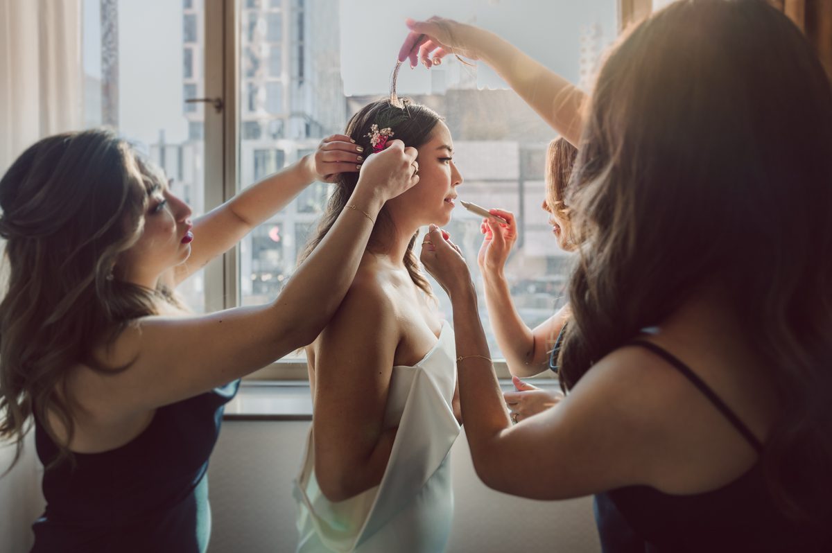 Duffield St, Brooklyn on November 19 even though it's Saturday morning it was still very busy. But luckily I found street parking right on Duffield St in front of Sheraton Downtown Brooklyn which was where I needed to be for Ariana and Jon's wedding prep. Vicky from VickyC5 hair/makeup team was there beautifying the ladies, I went straight to flat lays of Ariana's wedding details such as rings, jewelry and her wedding invitations. I use ribbons, extra loose flowers to make the flat lays more fine art looking. Once all the details are done, my full focus goes to the bride Ariana and her ladies. Ariana and Jon were planning to do a Chinese Door Game at the hotel room, so as soon as Ariana was ready in her Hanbok (Korean Traditional Wedding Outfit) Jon and his groomsmen arrived at the door. With Ariana's bridal suite crowded with too many people Ariana's bridesmaids started to give instructions to the games that Jon and his groomsmen need to play in order to get through the second door so that Jon can meet/see his bride Ariana. While the games are happening outside Ariana's door one of the bridesmaid has her phone on FaceTime so that Ariana can see how the men are doing during all the door games. I of course had my second shooter inside the room with Ariana to get her reactions which was hilarious. After the door games, we then moved to a conference room of at Sheraton Downtown Brooklyn for Ariana and Jon's Chinese Tea Pouring Ceremony (this is Jon's Chinese side's wedding tradition where you pour tea to all the elders in the family). Once all the Chines and Korean wedding traditions are over, we all rushed to Brooklyn Botanical Garden. Traffic from Sheraton Downtown Brooklyn to Brooklyn Botanical Garden was pretty bad, as usual. Once I arrived there of course was no street parking available near the entrance and parking lot for Brooklyn Botanical Garden was way too far for me to carry all the gears. After driving around I found one spot few blocks away from the Brooklyn Botanical Garden entrance. Brooklyn Botanical Garden was busy with Lightscape preparation and installation which we were not allowed to photograph so we were left with very little options for wedding portrait backdrop, plus it was COLD and we were looking light! These are important things to consider when you are planning for Winter wedding. I worked as quickly as possible with Ariana and Jon's first look and bridal party photos. Then we stayed inside for family photos since elders did not wanted to go outside which I totally don't blame. Then I quickly took Ariana and Jon outside for bit more couple's portraits then it was time for the wedding ceremony. Ariana and Jon's wedding ceremony held place at The Palm House at Brooklyn Botanical Garden, but because it was an winter wedding we've lost all the light and I had to use my video lights but over all the ceremony was beautiful and Oh Fleur NYC did absolutely an amazing job with ceremony decor (floral/candles). The Palm House was empty again, OhfleurNYC as well as Brooklyn Botanical Garden staff were busy turning the room. Oh Fleur NYC's Jessica's talent was amazing her usage of floral, choice of colors and mixing the floral with tall candles were magical. Turned The Palm House into a beautiful and romantic garden. Warmth of candles, peach and pinks of flowers all blended so well turning the Palm House at Brooklyn Botanical Garden in to fairytale floral ballroom. Ariana and Jon attended cocktail enjoying their time with friends and family before their wedding reception at The Palm House. Ariana and Jon's wedding at The Palm House at Brooklyn Botanical Garden documented by Karis from Hey Karis New York, Brooklyn, Hudson Valley and Catskills Wedding Photographer and NYC Elopement Photographer.