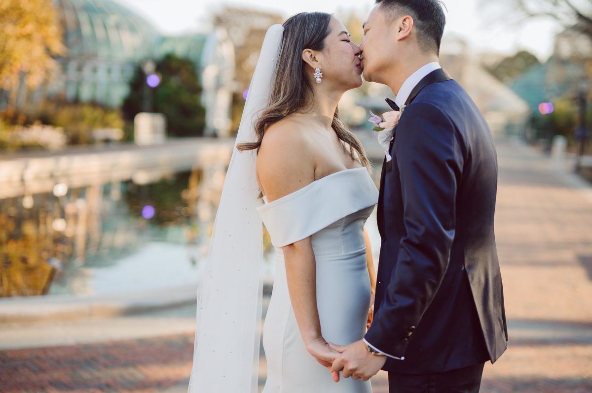 Duffield St, Brooklyn on November 19 even though it's Saturday morning it was still very busy. But luckily I found street parking right on Duffield St in front of Sheraton Downtown Brooklyn which was where I needed to be for Ariana and Jon's wedding prep. Vicky from VickyC5 hair/makeup team was there beautifying the ladies, I went straight to flat lays of Ariana's wedding details such as rings, jewelry and her wedding invitations. I use ribbons, extra loose flowers to make the flat lays more fine art looking. Once all the details are done, my full focus goes to the bride Ariana and her ladies. Ariana and Jon were planning to do a Chinese Door Game at the hotel room, so as soon as Ariana was ready in her Hanbok (Korean Traditional Wedding Outfit) Jon and his groomsmen arrived at the door. With Ariana's bridal suite crowded with too many people Ariana's bridesmaids started to give instructions to the games that Jon and his groomsmen need to play in order to get through the second door so that Jon can meet/see his bride Ariana. While the games are happening outside Ariana's door one of the bridesmaid has her phone on FaceTime so that Ariana can see how the men are doing during all the door games. I of course had my second shooter inside the room with Ariana to get her reactions which was hilarious. After the door games, we then moved to a conference room of at Sheraton Downtown Brooklyn for Ariana and Jon's Chinese Tea Pouring Ceremony (this is Jon's Chinese side's wedding tradition where you pour tea to all the elders in the family). Once all the Chines and Korean wedding traditions are over, we all rushed to Brooklyn Botanical Garden. Traffic from Sheraton Downtown Brooklyn to Brooklyn Botanical Garden was pretty bad, as usual. Once I arrived there of course was no street parking available near the entrance and parking lot for Brooklyn Botanical Garden was way too far for me to carry all the gears. After driving around I found one spot few blocks away from the Brooklyn Botanical Garden entrance. Brooklyn Botanical Garden was busy with Lightscape preparation and installation which we were not allowed to photograph so we were left with very little options for wedding portrait backdrop, plus it was COLD and we were looking light! These are important things to consider when you are planning for Winter wedding. I worked as quickly as possible with Ariana and Jon's first look and bridal party photos. Then we stayed inside for family photos since elders did not wanted to go outside which I totally don't blame. Then I quickly took Ariana and Jon outside for bit more couple's portraits then it was time for the wedding ceremony. Ariana and Jon's wedding ceremony held place at The Palm House at Brooklyn Botanical Garden, but because it was an winter wedding we've lost all the light and I had to use my video lights but over all the ceremony was beautiful and Oh Fleur NYC did absolutely an amazing job with ceremony decor (floral/candles). The Palm House was empty again, OhfleurNYC as well as Brooklyn Botanical Garden staff were busy turning the room. Oh Fleur NYC's Jessica's talent was amazing her usage of floral, choice of colors and mixing the floral with tall candles were magical. Turned The Palm House into a beautiful and romantic garden. Warmth of candles, peach and pinks of flowers all blended so well turning the Palm House at Brooklyn Botanical Garden in to fairytale floral ballroom. Ariana and Jon attended cocktail enjoying their time with friends and family before their wedding reception at The Palm House. Ariana and Jon's wedding at The Palm House at Brooklyn Botanical Garden documented by Karis from Hey Karis New York, Brooklyn, Hudson Valley and Catskills Wedding Photographer and NYC Elopement Photographer.