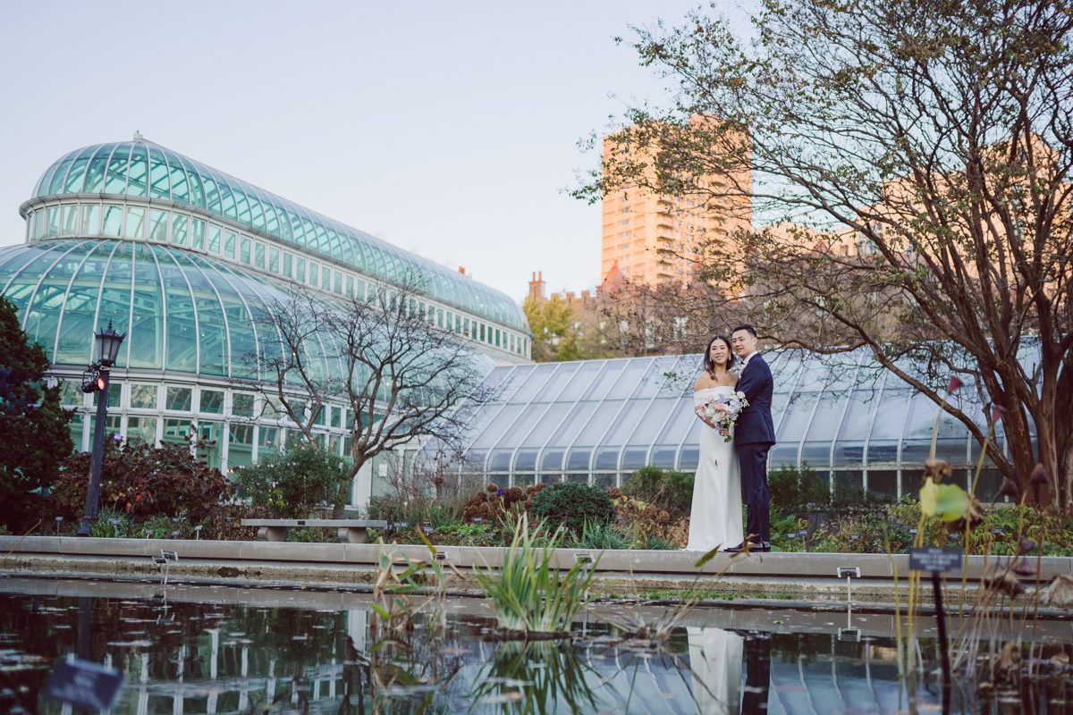Duffield St, Brooklyn on November 19 even though it's Saturday morning it was still very busy. But luckily I found street parking right on Duffield St in front of Sheraton Downtown Brooklyn which was where I needed to be for Ariana and Jon's wedding prep. Vicky from VickyC5 hair/makeup team was there beautifying the ladies, I went straight to flat lays of Ariana's wedding details such as rings, jewelry and her wedding invitations. I use ribbons, extra loose flowers to make the flat lays more fine art looking. Once all the details are done, my full focus goes to the bride Ariana and her ladies. Ariana and Jon were planning to do a Chinese Door Game at the hotel room, so as soon as Ariana was ready in her Hanbok (Korean Traditional Wedding Outfit) Jon and his groomsmen arrived at the door. With Ariana's bridal suite crowded with too many people Ariana's bridesmaids started to give instructions to the games that Jon and his groomsmen need to play in order to get through the second door so that Jon can meet/see his bride Ariana. While the games are happening outside Ariana's door one of the bridesmaid has her phone on FaceTime so that Ariana can see how the men are doing during all the door games. I of course had my second shooter inside the room with Ariana to get her reactions which was hilarious. After the door games, we then moved to a conference room of at Sheraton Downtown Brooklyn for Ariana and Jon's Chinese Tea Pouring Ceremony (this is Jon's Chinese side's wedding tradition where you pour tea to all the elders in the family). Once all the Chines and Korean wedding traditions are over, we all rushed to Brooklyn Botanical Garden. Traffic from Sheraton Downtown Brooklyn to Brooklyn Botanical Garden was pretty bad, as usual. Once I arrived there of course was no street parking available near the entrance and parking lot for Brooklyn Botanical Garden was way too far for me to carry all the gears. After driving around I found one spot few blocks away from the Brooklyn Botanical Garden entrance. Brooklyn Botanical Garden was busy with Lightscape preparation and installation which we were not allowed to photograph so we were left with very little options for wedding portrait backdrop, plus it was COLD and we were looking light! These are important things to consider when you are planning for Winter wedding. I worked as quickly as possible with Ariana and Jon's first look and bridal party photos. Then we stayed inside for family photos since elders did not wanted to go outside which I totally don't blame. Then I quickly took Ariana and Jon outside for bit more couple's portraits then it was time for the wedding ceremony. Ariana and Jon's wedding ceremony held place at The Palm House at Brooklyn Botanical Garden, but because it was an winter wedding we've lost all the light and I had to use my video lights but over all the ceremony was beautiful and Oh Fleur NYC did absolutely an amazing job with ceremony decor (floral/candles). The Palm House was empty again, OhfleurNYC as well as Brooklyn Botanical Garden staff were busy turning the room. Oh Fleur NYC's Jessica's talent was amazing her usage of floral, choice of colors and mixing the floral with tall candles were magical. Turned The Palm House into a beautiful and romantic garden. Warmth of candles, peach and pinks of flowers all blended so well turning the Palm House at Brooklyn Botanical Garden in to fairytale floral ballroom. Ariana and Jon attended cocktail enjoying their time with friends and family before their wedding reception at The Palm House. Ariana and Jon's wedding at The Palm House at Brooklyn Botanical Garden documented by Karis from Hey Karis New York, Brooklyn, Hudson Valley and Catskills Wedding Photographer and NYC Elopement Photographer.