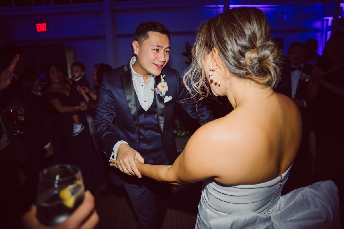 Duffield St, Brooklyn on November 19 even though it's Saturday morning it was still very busy. But luckily I found street parking right on Duffield St in front of Sheraton Downtown Brooklyn which was where I needed to be for Ariana and Jon's wedding prep. Vicky from VickyC5 hair/makeup team was there beautifying the ladies, I went straight to flat lays of Ariana's wedding details such as rings, jewelry and her wedding invitations. I use ribbons, extra loose flowers to make the flat lays more fine art looking. Once all the details are done, my full focus goes to the bride Ariana and her ladies. Ariana and Jon were planning to do a Chinese Door Game at the hotel room, so as soon as Ariana was ready in her Hanbok (Korean Traditional Wedding Outfit) Jon and his groomsmen arrived at the door. With Ariana's bridal suite crowded with too many people Ariana's bridesmaids started to give instructions to the games that Jon and his groomsmen need to play in order to get through the second door so that Jon can meet/see his bride Ariana. While the games are happening outside Ariana's door one of the bridesmaid has her phone on FaceTime so that Ariana can see how the men are doing during all the door games. I of course had my second shooter inside the room with Ariana to get her reactions which was hilarious. After the door games, we then moved to a conference room of at Sheraton Downtown Brooklyn for Ariana and Jon's Chinese Tea Pouring Ceremony (this is Jon's Chinese side's wedding tradition where you pour tea to all the elders in the family). Once all the Chines and Korean wedding traditions are over, we all rushed to Brooklyn Botanical Garden. Traffic from Sheraton Downtown Brooklyn to Brooklyn Botanical Garden was pretty bad, as usual. Once I arrived there of course was no street parking available near the entrance and parking lot for Brooklyn Botanical Garden was way too far for me to carry all the gears. After driving around I found one spot few blocks away from the Brooklyn Botanical Garden entrance. Brooklyn Botanical Garden was busy with Lightscape preparation and installation which we were not allowed to photograph so we were left with very little options for wedding portrait backdrop, plus it was COLD and we were looking light! These are important things to consider when you are planning for Winter wedding. I worked as quickly as possible with Ariana and Jon's first look and bridal party photos. Then we stayed inside for family photos since elders did not wanted to go outside which I totally don't blame. Then I quickly took Ariana and Jon outside for bit more couple's portraits then it was time for the wedding ceremony. Ariana and Jon's wedding ceremony held place at The Palm House at Brooklyn Botanical Garden, but because it was an winter wedding we've lost all the light and I had to use my video lights but over all the ceremony was beautiful and Oh Fleur NYC did absolutely an amazing job with ceremony decor (floral/candles). The Palm House was empty again, OhfleurNYC as well as Brooklyn Botanical Garden staff were busy turning the room. Oh Fleur NYC's Jessica's talent was amazing her usage of floral, choice of colors and mixing the floral with tall candles were magical. Turned The Palm House into a beautiful and romantic garden. Warmth of candles, peach and pinks of flowers all blended so well turning the Palm House at Brooklyn Botanical Garden in to fairytale floral ballroom. Ariana and Jon attended cocktail enjoying their time with friends and family before their wedding reception at The Palm House. Ariana and Jon's wedding at The Palm House at Brooklyn Botanical Garden documented by Karis from Hey Karis New York, Brooklyn, Hudson Valley and Catskills Wedding Photographer and NYC Elopement Photographer.