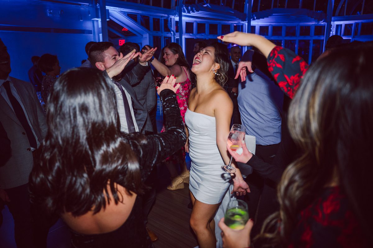 Duffield St, Brooklyn on November 19 even though it's Saturday morning it was still very busy. But luckily I found street parking right on Duffield St in front of Sheraton Downtown Brooklyn which was where I needed to be for Ariana and Jon's wedding prep. Vicky from VickyC5 hair/makeup team was there beautifying the ladies, I went straight to flat lays of Ariana's wedding details such as rings, jewelry and her wedding invitations. I use ribbons, extra loose flowers to make the flat lays more fine art looking. Once all the details are done, my full focus goes to the bride Ariana and her ladies. Ariana and Jon were planning to do a Chinese Door Game at the hotel room, so as soon as Ariana was ready in her Hanbok (Korean Traditional Wedding Outfit) Jon and his groomsmen arrived at the door. With Ariana's bridal suite crowded with too many people Ariana's bridesmaids started to give instructions to the games that Jon and his groomsmen need to play in order to get through the second door so that Jon can meet/see his bride Ariana. While the games are happening outside Ariana's door one of the bridesmaid has her phone on FaceTime so that Ariana can see how the men are doing during all the door games. I of course had my second shooter inside the room with Ariana to get her reactions which was hilarious. After the door games, we then moved to a conference room of at Sheraton Downtown Brooklyn for Ariana and Jon's Chinese Tea Pouring Ceremony (this is Jon's Chinese side's wedding tradition where you pour tea to all the elders in the family). Once all the Chines and Korean wedding traditions are over, we all rushed to Brooklyn Botanical Garden. Traffic from Sheraton Downtown Brooklyn to Brooklyn Botanical Garden was pretty bad, as usual. Once I arrived there of course was no street parking available near the entrance and parking lot for Brooklyn Botanical Garden was way too far for me to carry all the gears. After driving around I found one spot few blocks away from the Brooklyn Botanical Garden entrance. Brooklyn Botanical Garden was busy with Lightscape preparation and installation which we were not allowed to photograph so we were left with very little options for wedding portrait backdrop, plus it was COLD and we were looking light! These are important things to consider when you are planning for Winter wedding. I worked as quickly as possible with Ariana and Jon's first look and bridal party photos. Then we stayed inside for family photos since elders did not wanted to go outside which I totally don't blame. Then I quickly took Ariana and Jon outside for bit more couple's portraits then it was time for the wedding ceremony. Ariana and Jon's wedding ceremony held place at The Palm House at Brooklyn Botanical Garden, but because it was an winter wedding we've lost all the light and I had to use my video lights but over all the ceremony was beautiful and Oh Fleur NYC did absolutely an amazing job with ceremony decor (floral/candles). The Palm House was empty again, OhfleurNYC as well as Brooklyn Botanical Garden staff were busy turning the room. Oh Fleur NYC's Jessica's talent was amazing her usage of floral, choice of colors and mixing the floral with tall candles were magical. Turned The Palm House into a beautiful and romantic garden. Warmth of candles, peach and pinks of flowers all blended so well turning the Palm House at Brooklyn Botanical Garden in to fairytale floral ballroom. Ariana and Jon attended cocktail enjoying their time with friends and family before their wedding reception at The Palm House. Ariana and Jon's wedding at The Palm House at Brooklyn Botanical Garden documented by Karis from Hey Karis New York, Brooklyn, Hudson Valley and Catskills Wedding Photographer and NYC Elopement Photographer.