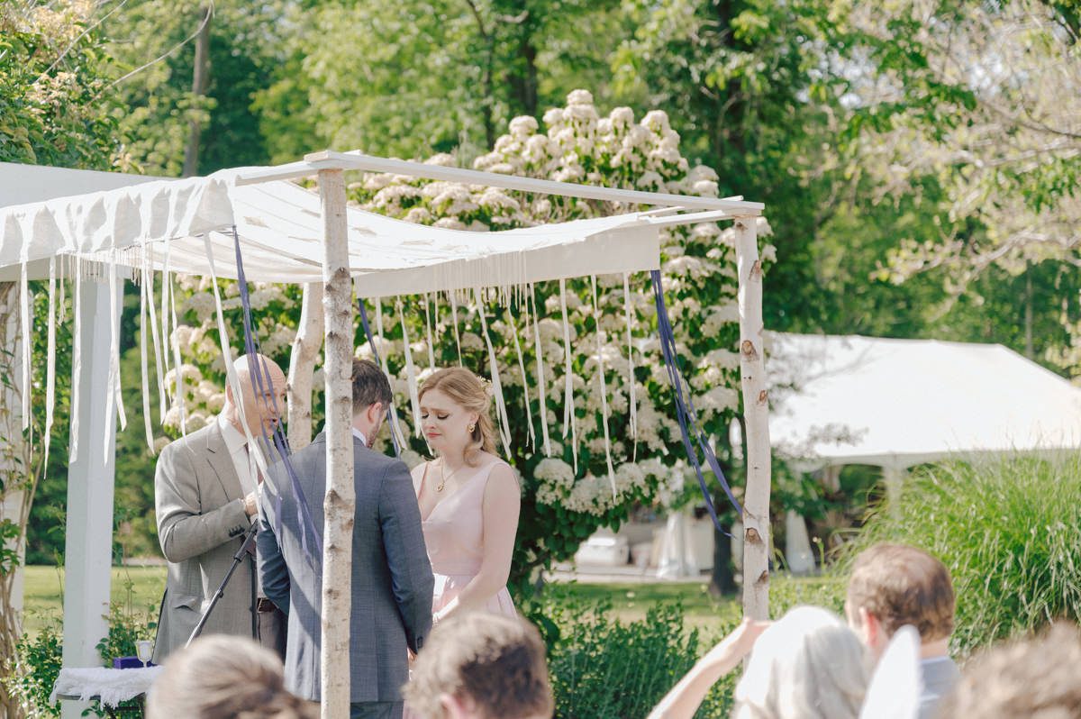 Woolverton Inn located in Stockton NJ is truly one of a kind magical place in NJ. Woolverton Inn is a bed and breakfast with 14 cottages and guest rooms which is perfect way to celebrate your wedding for the whole weekend with family and friends. Tara and Matt along with their family spent the whole weekend at Woolverton Inn celebrating their wedding. Tara and Matt's goal for their wedding was to have an intimate, chill and relaxed wedding weekend with their loved ones. No bridal party, no formalities, no rules but Tara and Matt only wanted to celebrate their wedding their way. No cheesy entrances, no sleazy DJ and no awkward parent dances, but instead they had a classic band "Dennis Pol Music" playing jazz music into the dark night. It was perfect weather, perfect evening to be having a tent wedding at Woolverton Inn. Tara and Matt woke up to get ready for their wedding at Woolverton Inn. Beauty and the Blush team was doing hair/makeup and soon Tara got into her pink Alexander McQueen wedding dress. I loved everything about Tara and Matt's wedding at Woolverton Inn from how chill and relaxed it was, Tara's pink Alexander McQueen wedding dress, and the fact that there was absolutely no bridal party! Focusing on the two people, bride and groom was only thing that mattered on Tara and Matt's wedding day. Tara and Matt's Woolverton Inn garden wedding ceremony was beautiful and sweet. Tara and Matt's cocktail hour at Woolverton Inn was like a gorgeous painting. Then when the cocktail hour ended guests walked along the path to the tent where the reception was held and on the way to the tent Tara and Matt stopped by the Sheep to get some photos with the adorable Woolverton Inn's most social most famous Miss Annie the sheep. Miss Annie is only sheep at Woolverton that is not afraid of people so when the snacks came out Miss Annie instantly ran over to tara and Matt. The rest of the evening, Tara and Matt walked around the tent talking to every single guests with amazing food and drinks Tara and Matt celebrated their wedding at Woolverton Inn exact way they wanted to and it was perfect! Tara and Matt's Woolverton Inn Stockton NJ wedding documented by by Karis | Hey Karis | Catskills, Hudson Valley NY elopement and wedding photographer | Brooklyn NY elopement and wedding photographer | Manhattan NY elopement and wedding photographer | Hey Karis is fun documentary wedding and elopement photographer.