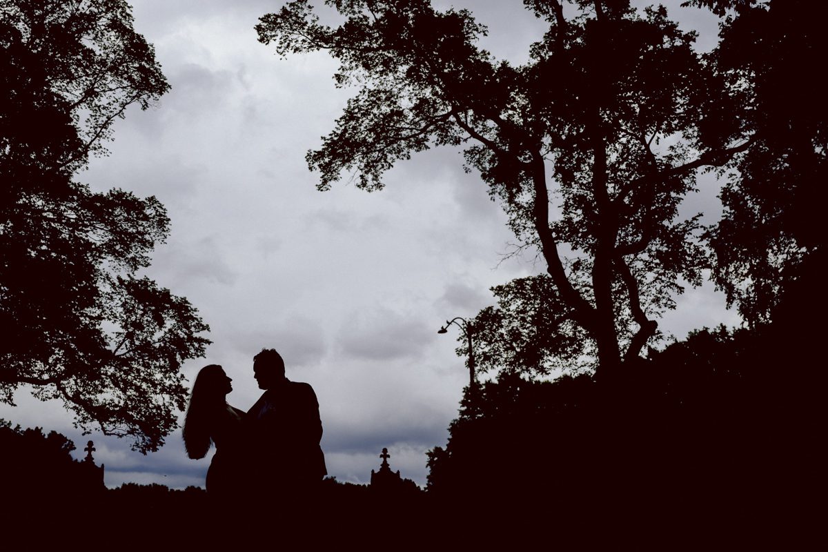 After trying to dodge multiple rains, scattered thunderstorms we met by Bethesda Fountain in Central Park NY. I saw Izzy and Brendan standing near crowded Bethesda Arcade. Dressed for their engagement session I took Izzy and Brendan to quiet corner of this jam packed Central Park. With maximum humidity in the air Izzy and Brendan was such a troopers in this heavy heat with crazy humidity in the air they smiles, laughed and cursed. The good ol'NY way, together with Izzy and Brendan we were weird, sarcastic, funny walking around Central Park. At some point it actually started drizzling then turned into heavy rain but we took covers under the trees and continued shooting. It was so fun photographing two people who cared less about how they looked in the humidity but just wanted to have fun! Again I love my careless, self loving humans and can't wait for Izzy and Brendan's wedding at Arrow Park this year. Izzy and Brendan's Central Park NY engagement documented by by Karis | Hey Karis | Catskills, Hudson Valley NY elopement and wedding photographer | Brooklyn NY elopement and wedding photographer | Manhattan NY elopement and wedding photographer | Hey Karis is fun documentary wedding and elopement photographer.