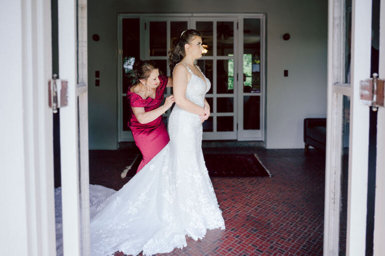 How do I explain the sincere and true feelings that Izzy and Brendan shared on their wedding day at one of the most magical place Arrow Park in Monroe NY. Izzy is Opera singer and Brendan is a Chef who owns his own restaurant called Circle in Newton, NJ got married at Arrow Park NY a month ago and it got real festive and wild real fast. But let's come back to the wild party in a bit and talk about their morning first. Izzy and Brendan both got ready onsite at Arrow Park, great thing about Arrow Park is that it has enough rooms to host all their bridal party and family. With all of Izzy and Brendan's loved ones onsite Izzy and Brendan's wedding prep was fun. No drama and no one running late, Izzy and Brendan's wedding prep went so smooth with everyone's cooperation! Izzy got into her dress with her mom and sister by her side, then we went down to the back steps for Izzy and Brendan's first look. Oh boy Brendan got super emotional for their first look, he couldn't even turn around to look at Izzy with all the happy emotions rushing to him. Izzy held his hand and they looked at each other. The two of them cried. Sharing such a beautiful first look Izzy and Brendan walked out to the front of Arrow Park for group and family photos. It was an August wedding so I kept everyone in the shade not too far, making it simple easy for group and family photos are important job to wedding photographer. After all the formal group photos were done, it was almost time for their wedding ceremony at the garden. Beautiful decor and floral arrangements were set up in the garden ready for Izzy and Brendan's wedding ceremony, guest started to walked down the long driveway and down the steps and found seats waited for the bride and groom to walk down the aisle. Brendan now standing in the front next to the priest, started tearing up as soon as he saw Izzy coming down the aisle escorted by her father. The two linked their eyes at each other and in the most loving way possible looked at each other through out the ceremony then sealed it with the first kiss as husband and wife. As calm and peaceful as Izzy and Brendan's wedding ceremony was, the two entered their reception each with (shaken) champagne bottles in their hands, everyone and anyone in Izzy and Brendan's way got sprayed with Champagne! They jumped, pouring Champagne into their friends mouth straight out of the bottle, then each drank some out of the bottle. Building the excitement in to their epic wedding party, Izzy and Brendan held each others hands and walked into the center of Arrow Park's courtyard and danced their first dance. Smoke and smell of freshly cooked dinner being prepared by Brendan's friends at Promises Kept Hudson Valley NY was filling the air, as first courses were being served. Happiest sound of plates, utensils and people chatting, Izzy and Brendan sat at their sweetheart table to enjoy their wedding dinner prepared by Promises Kept Hudson Valley NY. Then the evening got deeper and darker and vibe got stronger and crazier. Music got louder and everyone was in their element celebrating Izzy and Brendan on their wedding day. Izzy and Brendan's Arrow Park Monroe NY Wedding documented by by Karis | Hey Karis | Catskills, Hudson Valley NY elopement and wedding photographer | Brooklyn NY elopement and wedding photographer | Manhattan NY elopement and wedding photographer | Hey Karis is fun documentary wedding and elopement photographer.