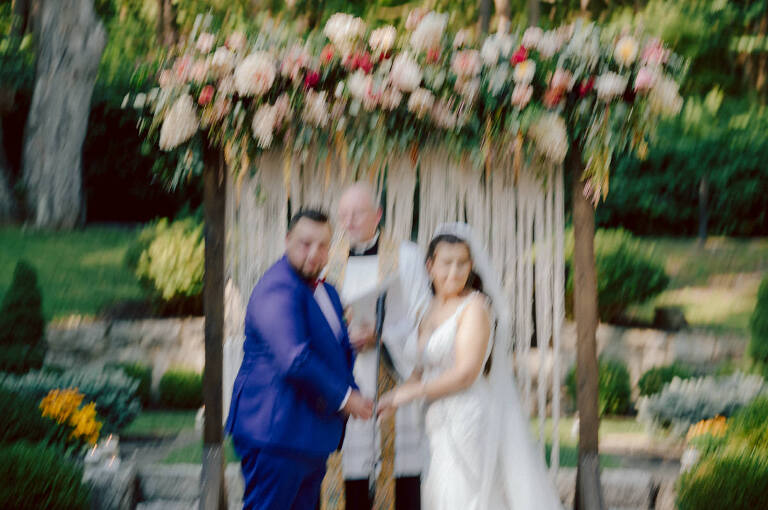 How do I explain the sincere and true feelings that Izzy and Brendan shared on their wedding day at one of the most magical place Arrow Park in Monroe NY. Izzy is Opera singer and Brendan is a Chef who owns his own restaurant called Circle in Newton, NJ got married at Arrow Park NY a month ago and it got real festive and wild real fast. But let's come back to the wild party in a bit and talk about their morning first. Izzy and Brendan both got ready onsite at Arrow Park, great thing about Arrow Park is that it has enough rooms to host all their bridal party and family. With all of Izzy and Brendan's loved ones onsite Izzy and Brendan's wedding prep was fun. No drama and no one running late, Izzy and Brendan's wedding prep went so smooth with everyone's cooperation! Izzy got into her dress with her mom and sister by her side, then we went down to the back steps for Izzy and Brendan's first look. Oh boy Brendan got super emotional for their first look, he couldn't even turn around to look at Izzy with all the happy emotions rushing to him. Izzy held his hand and they looked at each other. The two of them cried. Sharing such a beautiful first look Izzy and Brendan walked out to the front of Arrow Park for group and family photos. It was an August wedding so I kept everyone in the shade not too far, making it simple easy for group and family photos are important job to wedding photographer. After all the formal group photos were done, it was almost time for their wedding ceremony at the garden. Beautiful decor and floral arrangements were set up in the garden ready for Izzy and Brendan's wedding ceremony, guest started to walked down the long driveway and down the steps and found seats waited for the bride and groom to walk down the aisle. Brendan now standing in the front next to the priest, started tearing up as soon as he saw Izzy coming down the aisle escorted by her father. The two linked their eyes at each other and in the most loving way possible looked at each other through out the ceremony then sealed it with the first kiss as husband and wife. As calm and peaceful as Izzy and Brendan's wedding ceremony was, the two entered their reception each with (shaken) champagne bottles in their hands, everyone and anyone in Izzy and Brendan's way got sprayed with Champagne! They jumped, pouring Champagne into their friends mouth straight out of the bottle, then each drank some out of the bottle. Building the excitement in to their epic wedding party, Izzy and Brendan held each others hands and walked into the center of Arrow Park's courtyard and danced their first dance. Smoke and smell of freshly cooked dinner being prepared by Brendan's friends at Promises Kept Hudson Valley NY was filling the air, as first courses were being served. Happiest sound of plates, utensils and people chatting, Izzy and Brendan sat at their sweetheart table to enjoy their wedding dinner prepared by Promises Kept Hudson Valley NY. Then the evening got deeper and darker and vibe got stronger and crazier. Music got louder and everyone was in their element celebrating Izzy and Brendan on their wedding day. Izzy and Brendan's Arrow Park Monroe NY Wedding documented by by Karis | Hey Karis | Catskills, Hudson Valley NY elopement and wedding photographer | Brooklyn NY elopement and wedding photographer | Manhattan NY elopement and wedding photographer | Hey Karis is fun documentary wedding and elopement photographer.
