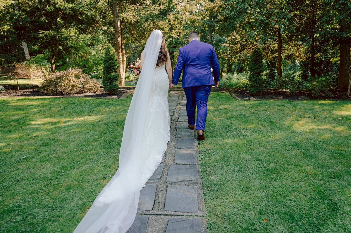 How do I explain the sincere and true feelings that Izzy and Brendan shared on their wedding day at one of the most magical place Arrow Park in Monroe NY. Izzy is Opera singer and Brendan is a Chef who owns his own restaurant called Circle in Newton, NJ got married at Arrow Park NY a month ago and it got real festive and wild real fast. But let's come back to the wild party in a bit and talk about their morning first. Izzy and Brendan both got ready onsite at Arrow Park, great thing about Arrow Park is that it has enough rooms to host all their bridal party and family. With all of Izzy and Brendan's loved ones onsite Izzy and Brendan's wedding prep was fun. No drama and no one running late, Izzy and Brendan's wedding prep went so smooth with everyone's cooperation! Izzy got into her dress with her mom and sister by her side, then we went down to the back steps for Izzy and Brendan's first look. Oh boy Brendan got super emotional for their first look, he couldn't even turn around to look at Izzy with all the happy emotions rushing to him. Izzy held his hand and they looked at each other. The two of them cried. Sharing such a beautiful first look Izzy and Brendan walked out to the front of Arrow Park for group and family photos. It was an August wedding so I kept everyone in the shade not too far, making it simple easy for group and family photos are important job to wedding photographer. After all the formal group photos were done, it was almost time for their wedding ceremony at the garden. Beautiful decor and floral arrangements were set up in the garden ready for Izzy and Brendan's wedding ceremony, guest started to walked down the long driveway and down the steps and found seats waited for the bride and groom to walk down the aisle. Brendan now standing in the front next to the priest, started tearing up as soon as he saw Izzy coming down the aisle escorted by her father. The two linked their eyes at each other and in the most loving way possible looked at each other through out the ceremony then sealed it with the first kiss as husband and wife. As calm and peaceful as Izzy and Brendan's wedding ceremony was, the two entered their reception each with (shaken) champagne bottles in their hands, everyone and anyone in Izzy and Brendan's way got sprayed with Champagne! They jumped, pouring Champagne into their friends mouth straight out of the bottle, then each drank some out of the bottle. Building the excitement in to their epic wedding party, Izzy and Brendan held each others hands and walked into the center of Arrow Park's courtyard and danced their first dance. Smoke and smell of freshly cooked dinner being prepared by Brendan's friends at Promises Kept Hudson Valley NY was filling the air, as first courses were being served. Happiest sound of plates, utensils and people chatting, Izzy and Brendan sat at their sweetheart table to enjoy their wedding dinner prepared by Promises Kept Hudson Valley NY. Then the evening got deeper and darker and vibe got stronger and crazier. Music got louder and everyone was in their element celebrating Izzy and Brendan on their wedding day. Izzy and Brendan's Arrow Park Monroe NY Wedding documented by by Karis | Hey Karis | Catskills, Hudson Valley NY elopement and wedding photographer | Brooklyn NY elopement and wedding photographer | Manhattan NY elopement and wedding photographer | Hey Karis is fun documentary wedding and elopement photographer.