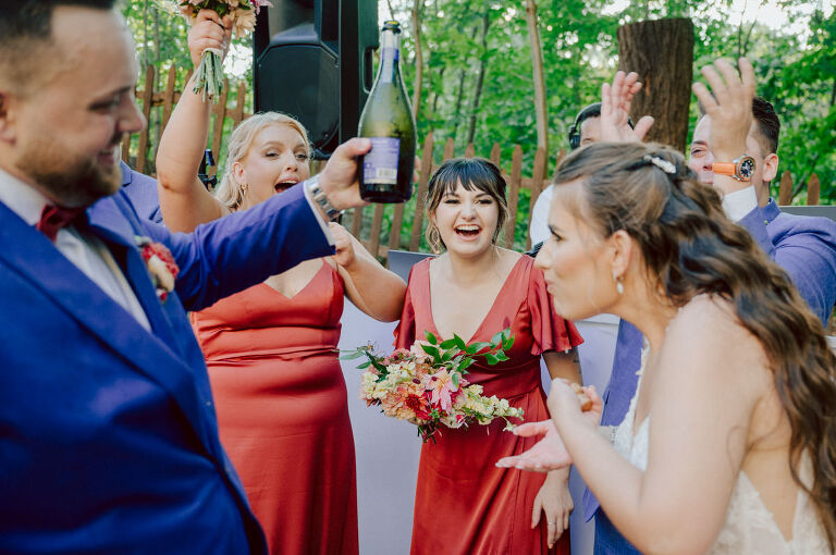 How do I explain the sincere and true feelings that Izzy and Brendan shared on their wedding day at one of the most magical place Arrow Park in Monroe NY. Izzy is Opera singer and Brendan is a Chef who owns his own restaurant called Circle in Newton, NJ got married at Arrow Park NY a month ago and it got real festive and wild real fast. But let's come back to the wild party in a bit and talk about their morning first. Izzy and Brendan both got ready onsite at Arrow Park, great thing about Arrow Park is that it has enough rooms to host all their bridal party and family. With all of Izzy and Brendan's loved ones onsite Izzy and Brendan's wedding prep was fun. No drama and no one running late, Izzy and Brendan's wedding prep went so smooth with everyone's cooperation! Izzy got into her dress with her mom and sister by her side, then we went down to the back steps for Izzy and Brendan's first look. Oh boy Brendan got super emotional for their first look, he couldn't even turn around to look at Izzy with all the happy emotions rushing to him. Izzy held his hand and they looked at each other. The two of them cried. Sharing such a beautiful first look Izzy and Brendan walked out to the front of Arrow Park for group and family photos. It was an August wedding so I kept everyone in the shade not too far, making it simple easy for group and family photos are important job to wedding photographer. After all the formal group photos were done, it was almost time for their wedding ceremony at the garden. Beautiful decor and floral arrangements were set up in the garden ready for Izzy and Brendan's wedding ceremony, guest started to walked down the long driveway and down the steps and found seats waited for the bride and groom to walk down the aisle. Brendan now standing in the front next to the priest, started tearing up as soon as he saw Izzy coming down the aisle escorted by her father. The two linked their eyes at each other and in the most loving way possible looked at each other through out the ceremony then sealed it with the first kiss as husband and wife. As calm and peaceful as Izzy and Brendan's wedding ceremony was, the two entered their reception each with (shaken) champagne bottles in their hands, everyone and anyone in Izzy and Brendan's way got sprayed with Champagne! They jumped, pouring Champagne into their friends mouth straight out of the bottle, then each drank some out of the bottle. Building the excitement in to their epic wedding party, Izzy and Brendan held each others hands and walked into the center of Arrow Park's courtyard and danced their first dance. Smoke and smell of freshly cooked dinner being prepared by Brendan's friends at Promises Kept Hudson Valley NY was filling the air, as first courses were being served. Happiest sound of plates, utensils and people chatting, Izzy and Brendan sat at their sweetheart table to enjoy their wedding dinner prepared by Promises Kept Hudson Valley NY. Then the evening got deeper and darker and vibe got stronger and crazier. Music got louder and everyone was in their element celebrating Izzy and Brendan on their wedding day. Izzy and Brendan's Arrow Park Monroe NY Wedding documented by by Karis | Hey Karis | Catskills, Hudson Valley NY elopement and wedding photographer | Brooklyn NY elopement and wedding photographer | Manhattan NY elopement and wedding photographer | Hey Karis is fun documentary wedding and elopement photographer.