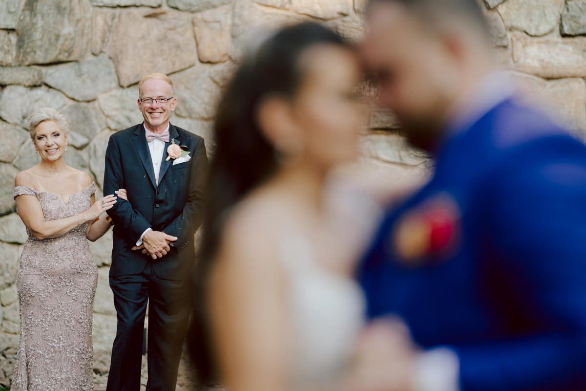 How do I explain the sincere and true feelings that Izzy and Brendan shared on their wedding day at one of the most magical place Arrow Park in Monroe NY. Izzy is Opera singer and Brendan is a Chef who owns his own restaurant called Circle in Newton, NJ got married at Arrow Park NY a month ago and it got real festive and wild real fast. But let's come back to the wild party in a bit and talk about their morning first. Izzy and Brendan both got ready onsite at Arrow Park, great thing about Arrow Park is that it has enough rooms to host all their bridal party and family. With all of Izzy and Brendan's loved ones onsite Izzy and Brendan's wedding prep was fun. No drama and no one running late, Izzy and Brendan's wedding prep went so smooth with everyone's cooperation! Izzy got into her dress with her mom and sister by her side, then we went down to the back steps for Izzy and Brendan's first look. Oh boy Brendan got super emotional for their first look, he couldn't even turn around to look at Izzy with all the happy emotions rushing to him. Izzy held his hand and they looked at each other. The two of them cried. Sharing such a beautiful first look Izzy and Brendan walked out to the front of Arrow Park for group and family photos. It was an August wedding so I kept everyone in the shade not too far, making it simple easy for group and family photos are important job to wedding photographer. After all the formal group photos were done, it was almost time for their wedding ceremony at the garden. Beautiful decor and floral arrangements were set up in the garden ready for Izzy and Brendan's wedding ceremony, guest started to walked down the long driveway and down the steps and found seats waited for the bride and groom to walk down the aisle. Brendan now standing in the front next to the priest, started tearing up as soon as he saw Izzy coming down the aisle escorted by her father. The two linked their eyes at each other and in the most loving way possible looked at each other through out the ceremony then sealed it with the first kiss as husband and wife. As calm and peaceful as Izzy and Brendan's wedding ceremony was, the two entered their reception each with (shaken) champagne bottles in their hands, everyone and anyone in Izzy and Brendan's way got sprayed with Champagne! They jumped, pouring Champagne into their friends mouth straight out of the bottle, then each drank some out of the bottle. Building the excitement in to their epic wedding party, Izzy and Brendan held each others hands and walked into the center of Arrow Park's courtyard and danced their first dance. Smoke and smell of freshly cooked dinner being prepared by Brendan's friends at Promises Kept Hudson Valley NY was filling the air, as first courses were being served. Happiest sound of plates, utensils and people chatting, Izzy and Brendan sat at their sweetheart table to enjoy their wedding dinner prepared by Promises Kept Hudson Valley NY. Then the evening got deeper and darker and vibe got stronger and crazier. Music got louder and everyone was in their element celebrating Izzy and Brendan on their wedding day. Izzy and Brendan's Arrow Park Monroe NY Wedding documented by by Karis | Hey Karis | Catskills, Hudson Valley NY elopement and wedding photographer | Brooklyn NY elopement and wedding photographer | Manhattan NY elopement and wedding photographer | Hey Karis is fun documentary wedding and elopement photographer.