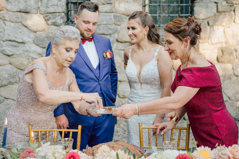 How do I explain the sincere and true feelings that Izzy and Brendan shared on their wedding day at one of the most magical place Arrow Park in Monroe NY. Izzy is Opera singer and Brendan is a Chef who owns his own restaurant called Circle in Newton, NJ got married at Arrow Park NY a month ago and it got real festive and wild real fast. But let's come back to the wild party in a bit and talk about their morning first. Izzy and Brendan both got ready onsite at Arrow Park, great thing about Arrow Park is that it has enough rooms to host all their bridal party and family. With all of Izzy and Brendan's loved ones onsite Izzy and Brendan's wedding prep was fun. No drama and no one running late, Izzy and Brendan's wedding prep went so smooth with everyone's cooperation! Izzy got into her dress with her mom and sister by her side, then we went down to the back steps for Izzy and Brendan's first look. Oh boy Brendan got super emotional for their first look, he couldn't even turn around to look at Izzy with all the happy emotions rushing to him. Izzy held his hand and they looked at each other. The two of them cried. Sharing such a beautiful first look Izzy and Brendan walked out to the front of Arrow Park for group and family photos. It was an August wedding so I kept everyone in the shade not too far, making it simple easy for group and family photos are important job to wedding photographer. After all the formal group photos were done, it was almost time for their wedding ceremony at the garden. Beautiful decor and floral arrangements were set up in the garden ready for Izzy and Brendan's wedding ceremony, guest started to walked down the long driveway and down the steps and found seats waited for the bride and groom to walk down the aisle. Brendan now standing in the front next to the priest, started tearing up as soon as he saw Izzy coming down the aisle escorted by her father. The two linked their eyes at each other and in the most loving way possible looked at each other through out the ceremony then sealed it with the first kiss as husband and wife. As calm and peaceful as Izzy and Brendan's wedding ceremony was, the two entered their reception each with (shaken) champagne bottles in their hands, everyone and anyone in Izzy and Brendan's way got sprayed with Champagne! They jumped, pouring Champagne into their friends mouth straight out of the bottle, then each drank some out of the bottle. Building the excitement in to their epic wedding party, Izzy and Brendan held each others hands and walked into the center of Arrow Park's courtyard and danced their first dance. Smoke and smell of freshly cooked dinner being prepared by Brendan's friends at Promises Kept Hudson Valley NY was filling the air, as first courses were being served. Happiest sound of plates, utensils and people chatting, Izzy and Brendan sat at their sweetheart table to enjoy their wedding dinner prepared by Promises Kept Hudson Valley NY. Then the evening got deeper and darker and vibe got stronger and crazier. Music got louder and everyone was in their element celebrating Izzy and Brendan on their wedding day. Izzy and Brendan's Arrow Park Monroe NY Wedding documented by by Karis | Hey Karis | Catskills, Hudson Valley NY elopement and wedding photographer | Brooklyn NY elopement and wedding photographer | Manhattan NY elopement and wedding photographer | Hey Karis is fun documentary wedding and elopement photographer.