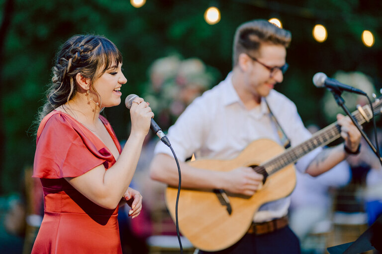 How do I explain the sincere and true feelings that Izzy and Brendan shared on their wedding day at one of the most magical place Arrow Park in Monroe NY. Izzy is Opera singer and Brendan is a Chef who owns his own restaurant called Circle in Newton, NJ got married at Arrow Park NY a month ago and it got real festive and wild real fast. But let's come back to the wild party in a bit and talk about their morning first. Izzy and Brendan both got ready onsite at Arrow Park, great thing about Arrow Park is that it has enough rooms to host all their bridal party and family. With all of Izzy and Brendan's loved ones onsite Izzy and Brendan's wedding prep was fun. No drama and no one running late, Izzy and Brendan's wedding prep went so smooth with everyone's cooperation! Izzy got into her dress with her mom and sister by her side, then we went down to the back steps for Izzy and Brendan's first look. Oh boy Brendan got super emotional for their first look, he couldn't even turn around to look at Izzy with all the happy emotions rushing to him. Izzy held his hand and they looked at each other. The two of them cried. Sharing such a beautiful first look Izzy and Brendan walked out to the front of Arrow Park for group and family photos. It was an August wedding so I kept everyone in the shade not too far, making it simple easy for group and family photos are important job to wedding photographer. After all the formal group photos were done, it was almost time for their wedding ceremony at the garden. Beautiful decor and floral arrangements were set up in the garden ready for Izzy and Brendan's wedding ceremony, guest started to walked down the long driveway and down the steps and found seats waited for the bride and groom to walk down the aisle. Brendan now standing in the front next to the priest, started tearing up as soon as he saw Izzy coming down the aisle escorted by her father. The two linked their eyes at each other and in the most loving way possible looked at each other through out the ceremony then sealed it with the first kiss as husband and wife. As calm and peaceful as Izzy and Brendan's wedding ceremony was, the two entered their reception each with (shaken) champagne bottles in their hands, everyone and anyone in Izzy and Brendan's way got sprayed with Champagne! They jumped, pouring Champagne into their friends mouth straight out of the bottle, then each drank some out of the bottle. Building the excitement in to their epic wedding party, Izzy and Brendan held each others hands and walked into the center of Arrow Park's courtyard and danced their first dance. Smoke and smell of freshly cooked dinner being prepared by Brendan's friends at Promises Kept Hudson Valley NY was filling the air, as first courses were being served. Happiest sound of plates, utensils and people chatting, Izzy and Brendan sat at their sweetheart table to enjoy their wedding dinner prepared by Promises Kept Hudson Valley NY. Then the evening got deeper and darker and vibe got stronger and crazier. Music got louder and everyone was in their element celebrating Izzy and Brendan on their wedding day. Izzy and Brendan's Arrow Park Monroe NY Wedding documented by by Karis | Hey Karis | Catskills, Hudson Valley NY elopement and wedding photographer | Brooklyn NY elopement and wedding photographer | Manhattan NY elopement and wedding photographer | Hey Karis is fun documentary wedding and elopement photographer.