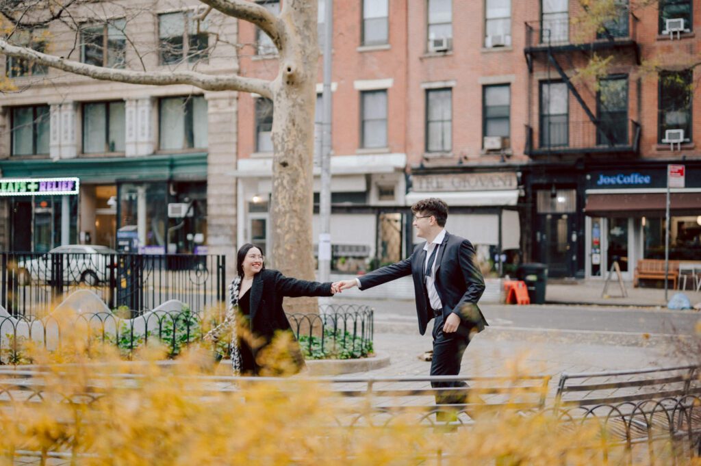 The city streets were refreshingly empty and surreal on an early Saturday morning in chilly December. With all the college students away for winter break, Washington Square Park, surrounded by NYU buildings and dorms, was particularly deserted. Erika and Andrei arrived around 7:30 am, stepping out of their Uber to meet me at the iconic Washington Square Arch. Erika looked stunning in a black velvet romper, while Andrei sported a tuxedo with a "purposely" undone bowtie, creating that effortlessly cool rockstar look for the morning. Together, we ventured through the chilly, deserted streets of Greenwich Village, making our way to Bond Street and concluding the engagement session in the vibrant East Village by the cube. Along the way, we spontaneously paused at corners, benches, and in front of unique buildings, capturing the essence of their love against the backdrop of the city. Erika and Andrei's engagement session in Greenwich Village was truly delightful, and I find myself eagerly anticipating their wedding next year at The Box House Hotel in Brooklyn—a venue that has long been on my bucket list. The blend of the picturesque Greenwich Village streets and the upcoming wedding at such a coveted location promises a celebration filled with love and unforgettable moments. Erika and Andrei's Washington Square Park NYC, Washington Mews NYC, Greenwich Village NYC documented by by Karis | Hey Karis | Destination Wedding Photographer | Manhattan, Catskills, Hudson Valley, Brooklyn and NJ | Destination Elopement, Destination Wedding Photographer | Hey Karis is fun documentary wedding and elopement photographer based in NY, NJ.