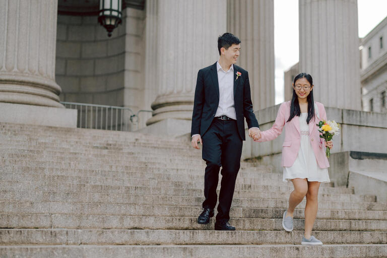 Alicia and Kevin made the bold decision to elope in the heart of the Big Apple before bidding adieu to city life and embracing suburban tranquility in New Jersey. Their choice resonates; after all, there's something undeniably magnetic about tying the knot in NYC that sets it apart from anywhere else in the world.
Less than two weeks before their planned elopement at NYC City Hall, Alicia and Kevin reached out to me. I promptly scheduled a call to delve into the details, eager to understand their vision and expectations for their special day. It was essential for me to grasp their vibe and personalities; forging this connection and building relationship before the big day is super important to me.
On April 5, I rendezvoused with Alicia and Kevin outside The Office of the City Clerk - Marriage Bureau. Despite hoping for a warm, sunny day, the brisk April air lingered, accompanied by a chilly breeze. Accompanied by a friend who served as their witness, we walked into the building.
My camera was ready from outside documenting Alicia and Kevin, as I wanted to tell their story from beginning to end. 
Inside, we navigated the bureaucratic procedures, clicking away at Alicia and Kevin as they pleasantly waited for their number to be called. With paperwork signed and formalities concluded, Alicia and Kevin became husband and wife in the blink of an eye.
We stayed a while longer inside the marriage bureau took the opportunity to capture some timeless moments posing on the iconic green sofa and NYC City Hall wall mural. Then we journeyed outside and wandered the vibrant bustling streets of NYC for some more photos. And what better way to conclude Alicia and Kevin's NYC City Hall elopement than with a quintessential New York slice.
Alicia and Kevin NYC City Hall NY Elopement documented by by Karis | Hey Karis | Destination Wedding Photographer | Manhattan, Catskills, Hudson Valley, Brooklyn and NJ | Destination Elopement, Destination Wedding Photographer | Hey Karis is fun documentary wedding and elopement photographer based in NY, NJ.
