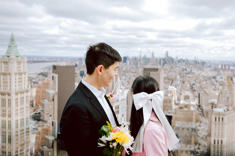 Alicia and Kevin made the bold decision to elope in the heart of the Big Apple before bidding adieu to city life and embracing suburban tranquility in New Jersey. Their choice resonates; after all, there's something undeniably magnetic about tying the knot in NYC that sets it apart from anywhere else in the world. Less than two weeks before their planned elopement at NYC City Hall, Alicia and Kevin reached out to me. I promptly scheduled a call to delve into the details, eager to understand their vision and expectations for their special day. It was essential for me to grasp their vibe and personalities; forging this connection and building relationship before the big day is super important to me. On April 5, I rendezvoused with Alicia and Kevin outside The Office of the City Clerk - Marriage Bureau. Despite hoping for a warm, sunny day, the brisk April air lingered, accompanied by a chilly breeze. Accompanied by a friend who served as their witness, we walked into the building. My camera was ready from outside documenting Alicia and Kevin, as I wanted to tell their story from beginning to end. Inside, we navigated the bureaucratic procedures, clicking away at Alicia and Kevin as they pleasantly waited for their number to be called. With paperwork signed and formalities concluded, Alicia and Kevin became husband and wife in the blink of an eye. We stayed a while longer inside the marriage bureau took the opportunity to capture some timeless moments posing on the iconic green sofa and NYC City Hall wall mural. Then we journeyed outside and wandered the vibrant bustling streets of NYC for some more photos. And what better way to conclude Alicia and Kevin's NYC City Hall elopement than with a quintessential New York slice. Alicia and Kevin NYC City Hall NY Elopement documented by by Karis | Hey Karis | Destination Wedding Photographer | Manhattan, Catskills, Hudson Valley, Brooklyn and NJ | Destination Elopement, Destination Wedding Photographer | Hey Karis is fun documentary wedding and elopement photographer based in NY, NJ.