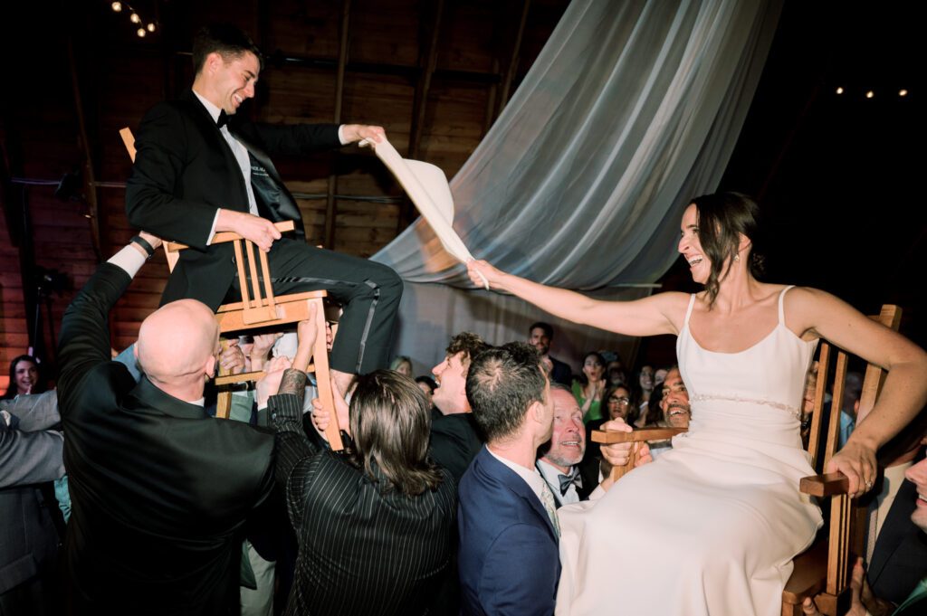 Malia and Aidan, currently residing in DC with their beloved pup Max, envisioned a wedding that reflected their laid-back, natural style. When we first chatted back in February 2023, they emphasized their desire for relaxed, fun, and candid photos that captured genuine moments.
Choosing The Barn at Perona Farms was a perfect fit for Malia and Aidan. Nestled amidst charming rustic surroundings and abundant nature, the venue complemented their preference for an authentic and unposed wedding day experience.
The ceremony took place outdoors on the lush lawn of The Barn at Perona Farms, exactly as they had envisioned – sweet, whimsy, and just the way they wanted it. Guests enjoyed a leisurely cocktail hour accompanied by live music courtesy of the talented Blue Label Band. The air was filled with the sounds of laughter and the clinking of wine glasses as everyone soaked in the joyful atmosphere.
As the evening progressed upstairs at The Barn, the ambiance was transformed by Moonlit Acres' stunning floral arrangements, candles, and elegant drapes. The space slowly filled with guests, reconnecting and sharing stories, delighted to be together again.
Then, the moment everyone had been waiting for: Malia and Aidan entered the room, surrounded by loved ones, and shared their first dance together.
Malia and Aidan's The Barn at Perona Farms NJ wedding documented by by Karis | Hey Karis | Destination Wedding Photographer | Manhattan, Catskills, Hudson Valley, Brooklyn and NJ | Destination Elopement, Destination Wedding Photographer | Hey Karis is fun documentary wedding and elopement photographer based in NY, NJ.