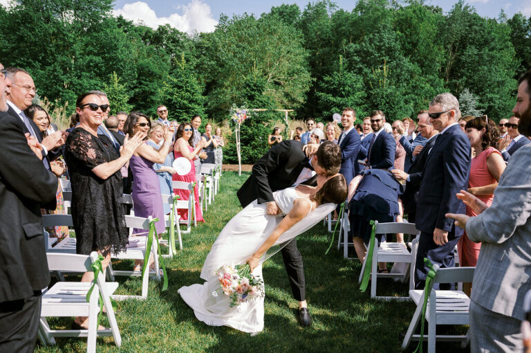 Malia and Aidan, currently residing in DC with their beloved pup Max, envisioned a wedding that reflected their laid-back, natural style. When we first chatted back in February 2023, they emphasized their desire for relaxed, fun, and candid photos that captured genuine moments.
Choosing The Barn at Perona Farms was a perfect fit for Malia and Aidan. Nestled amidst charming rustic surroundings and abundant nature, the venue complemented their preference for an authentic and unposed wedding day experience.
The ceremony took place outdoors on the lush lawn of The Barn at Perona Farms, exactly as they had envisioned – sweet, whimsy, and just the way they wanted it. Guests enjoyed a leisurely cocktail hour accompanied by live music courtesy of the talented Blue Label Band. The air was filled with the sounds of laughter and the clinking of wine glasses as everyone soaked in the joyful atmosphere.
As the evening progressed upstairs at The Barn, the ambiance was transformed by Moonlit Acres' stunning floral arrangements, candles, and elegant drapes. The space slowly filled with guests, reconnecting and sharing stories, delighted to be together again.
Then, the moment everyone had been waiting for: Malia and Aidan entered the room, surrounded by loved ones, and shared their first dance together.
Malia and Aidan's The Barn at Perona Farms NJ wedding documented by by Karis | Hey Karis | Destination Wedding Photographer | Manhattan, Catskills, Hudson Valley, Brooklyn and NJ | Destination Elopement, Destination Wedding Photographer | Hey Karis is fun documentary wedding and elopement photographer based in NY, NJ.