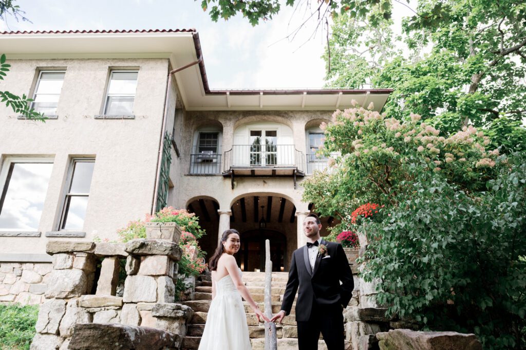 Vivian and Josh’s Gorgeous September Wedding at Arrow Park, NY
There’s something truly special about Arrow Park—it feels like my home away from home, and Vivian and Josh’s beautiful September wedding perfectly showcased everything this venue has to offer. Their blended celebration, honoring Vivian’s Korean heritage and Josh’s Jewish background, was a heartfelt and unforgettable day.
The couple beautifully wove their cultures into the festivities, from breaking the glass at the end of their garden ceremony to the lively horah during the reception. Later, Vivian and Josh delighted their guests by changing into traditional Korean hanbok outfits, a touching nod to her heritage.
Arrow Park: A Dream Venue for Multi-Day WeddingsVivian, Josh, and their loved ones all got ready at Arrow Park, which offers plenty of spacious accommodations for family and friends. This made it the perfect choice for their multi-day celebration. With its stunning grounds and versatile spaces, Arrow Park is ideal for couples seeking a wedding weekend filled with both elegance and comfort.
A Scenic September CelebrationThanks to the pleasant September weather, Vivian and Josh made full use of Arrow Park’s breathtaking grounds. Their day began with a magical first look along the iconic driveway lined with towering trees. From there, we explored the garden with its charming sculptures, captured moments by the ceremony’s floral décor, and took stunning portraits on the mansion’s iconic back staircase bathed in perfect lighting. We also ventured indoors for photos in the library and the Green Room, taking advantage of the mansion’s timeless charm.
As family and friends gathered, we captured formal portraits in front of the grand mansion before the ceremony began.
A Ceremony and Reception to RememberThe ceremony was set in the picturesque garden, where Jenny from Field Trip Flowers created a breathtaking floral backdrop that perfectly complemented the natural beauty of Arrow Park.
Afterward, guests strolled back to the mansion for a warm and inviting cocktail hour on the main floor. Later, everyone gathered in the courtyard for an enchanting outdoor reception under twinkling café lights. The space felt intimate yet grand, with the perfect blend of rustic elegance and romance.
Arrow Park’s charm, coupled with Vivian and Josh’s thoughtful cultural details, made this wedding one to remember. It’s the kind of venue where dreams come true—a hidden gem that’s ready to host your perfect day.
  
Thankful for all the wedding vendors that made this day possible:⁠
Venue: @arrowparkny
Floral: @fieldtripflowers
Catering: @lovenrosemary

Vivian and Josh Arrow Park NY Wedding documented by Karis from Hey Karis New York, Brooklyn, Hudson Valley NY and Catskills NY and NJ Wedding and NYC Elopement Photographer.