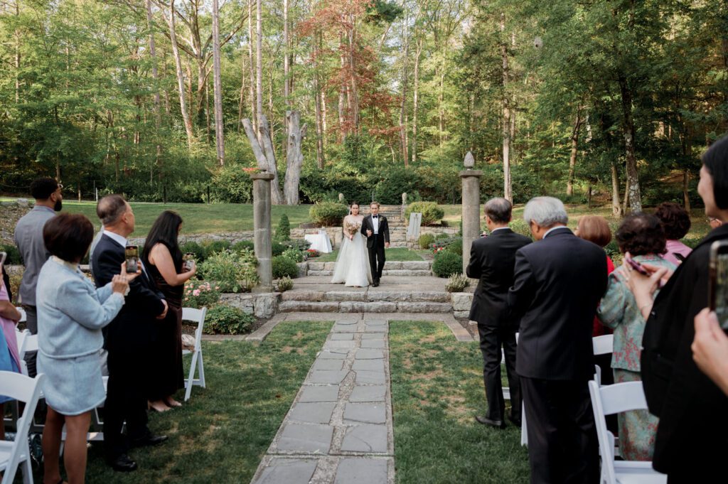 Vivian and Josh’s Gorgeous September Wedding at Arrow Park, NY
There’s something truly special about Arrow Park—it feels like my home away from home, and Vivian and Josh’s beautiful September wedding perfectly showcased everything this venue has to offer. Their blended celebration, honoring Vivian’s Korean heritage and Josh’s Jewish background, was a heartfelt and unforgettable day.
The couple beautifully wove their cultures into the festivities, from breaking the glass at the end of their garden ceremony to the lively horah during the reception. Later, Vivian and Josh delighted their guests by changing into traditional Korean hanbok outfits, a touching nod to her heritage.
Arrow Park: A Dream Venue for Multi-Day WeddingsVivian, Josh, and their loved ones all got ready at Arrow Park, which offers plenty of spacious accommodations for family and friends. This made it the perfect choice for their multi-day celebration. With its stunning grounds and versatile spaces, Arrow Park is ideal for couples seeking a wedding weekend filled with both elegance and comfort.
A Scenic September CelebrationThanks to the pleasant September weather, Vivian and Josh made full use of Arrow Park’s breathtaking grounds. Their day began with a magical first look along the iconic driveway lined with towering trees. From there, we explored the garden with its charming sculptures, captured moments by the ceremony’s floral décor, and took stunning portraits on the mansion’s iconic back staircase bathed in perfect lighting. We also ventured indoors for photos in the library and the Green Room, taking advantage of the mansion’s timeless charm.
As family and friends gathered, we captured formal portraits in front of the grand mansion before the ceremony began.
A Ceremony and Reception to RememberThe ceremony was set in the picturesque garden, where Jenny from Field Trip Flowers created a breathtaking floral backdrop that perfectly complemented the natural beauty of Arrow Park.
Afterward, guests strolled back to the mansion for a warm and inviting cocktail hour on the main floor. Later, everyone gathered in the courtyard for an enchanting outdoor reception under twinkling café lights. The space felt intimate yet grand, with the perfect blend of rustic elegance and romance.
Arrow Park’s charm, coupled with Vivian and Josh’s thoughtful cultural details, made this wedding one to remember. It’s the kind of venue where dreams come true—a hidden gem that’s ready to host your perfect day.
  
Thankful for all the wedding vendors that made this day possible:⁠
Venue: @arrowparkny
Floral: @fieldtripflowers
Catering: @lovenrosemary

Vivian and Josh Arrow Park NY Wedding documented by Karis from Hey Karis New York, Brooklyn, Hudson Valley NY and Catskills NY and NJ Wedding and NYC Elopement Photographer.