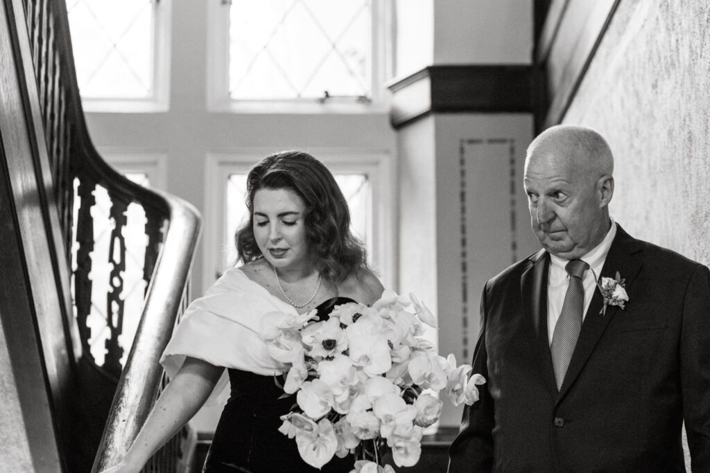 Kirsten and AJ’s September Wedding at Arrow Park, NY
Kirsten and AJ’s wedding day was a bit chilly and rainy, but their flexibility and positivity turned the day into a magical celebration. Originally planned for the garden, the ceremony was moved indoors due to the autumn rain. The staff at Arrow Park seamlessly transitioned the setup to the mansion’s main floor, creating an intimate and elegant ceremony space. The historic charm of the mansion, with its grand details and warm ambiance, added a cozy, romantic touch to their special day.
Kirsten, a talented fashion designer, surprised everyone—including her groom, AJ—by wearing a stunning black velvet strapless dress with an oversized white bow draping dramatically down the back. She designed the dress herself, and it was a show-stopper that perfectly reflected her unique style. The ceremony was heartfelt and personal, with family and friends gathering close to witness Kirsten and AJ’s vows.
After the ceremony, the main mansion was transformed to host a lively cocktail hour. Guests mingled and enjoyed delicious hors d'oeuvres while the reception space in the pavilion was being prepared. Kirsten and AJ’s attention to detail shone through in their décor choices, including the black-and-white checkered flooring that gave the pavilion a retro vibe. It was a perfect blend of modern chic and classic sophistication.
The reception began with Kirsten and AJ’s grand entrance, greeted by cheers from their guests. Their first dance was sweet and endearing, setting the tone for a night of joy and celebration. As the evening progressed, the party ramped up with enthusiastic dancing, heartfelt toasts, and even a surprise performance—a few uncles took the mic for an impromptu rap song that brought the house down.
Arrow Park provided the perfect backdrop for Kirsten and AJ’s wedding. With its blend of natural beauty and historic architecture, it’s an ideal venue for couples seeking a mix of indoor and outdoor spaces. The mansion offers a timeless elegance, while the pavilion provides a versatile setting for larger receptions.
Planning Tips for Future Couples at Arrow Park:
1. Have a Rain Plan: September weather can be unpredictable, so work with the Arrow Park staff to plan for both indoor and outdoor options. The mansion’s interiors provide a stunning alternative for ceremonies or cocktail hours.
2. Maximize the Pavilion: The pavilion’s spacious layout can accommodate various themes and setups. Consider unique flooring, lighting, or drapery to make the space your own.
3. Embrace the Venue’s Charm: Use the mansion’s historic features—like the fireplaces and vintage decor—as part of your wedding aesthetic. It’s a built-in backdrop that needs little embellishment.
4. Plan Time for Photos: Arrow Park’s grounds are breathtaking, especially in the fall. Schedule time with your photographer to capture the beauty of the lake, gardens, and mansion.
Kirsten and AJ’s wedding was a true testament to the power of creativity, adaptability, and love. Their celebration at Arrow Park was unforgettable, and I’m grateful to have been a part of their special day.
Thankful for all the wedding vendors that made this day possible:⁠
Venue: @arrowparkny
Catering: @lovenrosemary
Kirsten and AJ Arrow Park NY Wedding documented by Karis from Hey Karis New York, Brooklyn, Hudson Valley NY and Catskills NY and NJ Wedding and NYC Elopement Photographer.