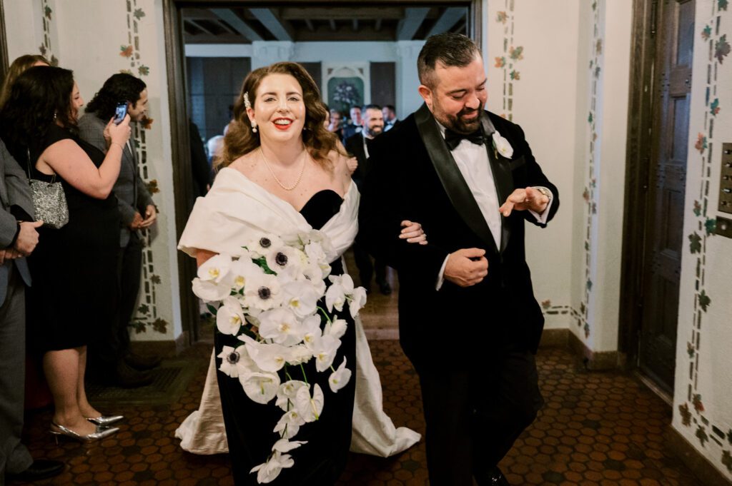 Kirsten and AJ’s September Wedding at Arrow Park, NY
Kirsten and AJ’s wedding day was a bit chilly and rainy, but their flexibility and positivity turned the day into a magical celebration. Originally planned for the garden, the ceremony was moved indoors due to the autumn rain. The staff at Arrow Park seamlessly transitioned the setup to the mansion’s main floor, creating an intimate and elegant ceremony space. The historic charm of the mansion, with its grand details and warm ambiance, added a cozy, romantic touch to their special day.
Kirsten, a talented fashion designer, surprised everyone—including her groom, AJ—by wearing a stunning black velvet strapless dress with an oversized white bow draping dramatically down the back. She designed the dress herself, and it was a show-stopper that perfectly reflected her unique style. The ceremony was heartfelt and personal, with family and friends gathering close to witness Kirsten and AJ’s vows.
After the ceremony, the main mansion was transformed to host a lively cocktail hour. Guests mingled and enjoyed delicious hors d'oeuvres while the reception space in the pavilion was being prepared. Kirsten and AJ’s attention to detail shone through in their décor choices, including the black-and-white checkered flooring that gave the pavilion a retro vibe. It was a perfect blend of modern chic and classic sophistication.
The reception began with Kirsten and AJ’s grand entrance, greeted by cheers from their guests. Their first dance was sweet and endearing, setting the tone for a night of joy and celebration. As the evening progressed, the party ramped up with enthusiastic dancing, heartfelt toasts, and even a surprise performance—a few uncles took the mic for an impromptu rap song that brought the house down.
Arrow Park provided the perfect backdrop for Kirsten and AJ’s wedding. With its blend of natural beauty and historic architecture, it’s an ideal venue for couples seeking a mix of indoor and outdoor spaces. The mansion offers a timeless elegance, while the pavilion provides a versatile setting for larger receptions.
Planning Tips for Future Couples at Arrow Park:
1. Have a Rain Plan: September weather can be unpredictable, so work with the Arrow Park staff to plan for both indoor and outdoor options. The mansion’s interiors provide a stunning alternative for ceremonies or cocktail hours.
2. Maximize the Pavilion: The pavilion’s spacious layout can accommodate various themes and setups. Consider unique flooring, lighting, or drapery to make the space your own.
3. Embrace the Venue’s Charm: Use the mansion’s historic features—like the fireplaces and vintage decor—as part of your wedding aesthetic. It’s a built-in backdrop that needs little embellishment.
4. Plan Time for Photos: Arrow Park’s grounds are breathtaking, especially in the fall. Schedule time with your photographer to capture the beauty of the lake, gardens, and mansion.
Kirsten and AJ’s wedding was a true testament to the power of creativity, adaptability, and love. Their celebration at Arrow Park was unforgettable, and I’m grateful to have been a part of their special day.
Thankful for all the wedding vendors that made this day possible:⁠
Venue: @arrowparkny
Catering: @lovenrosemary
Kirsten and AJ Arrow Park NY Wedding documented by Karis from Hey Karis New York, Brooklyn, Hudson Valley NY and Catskills NY and NJ Wedding and NYC Elopement Photographer.